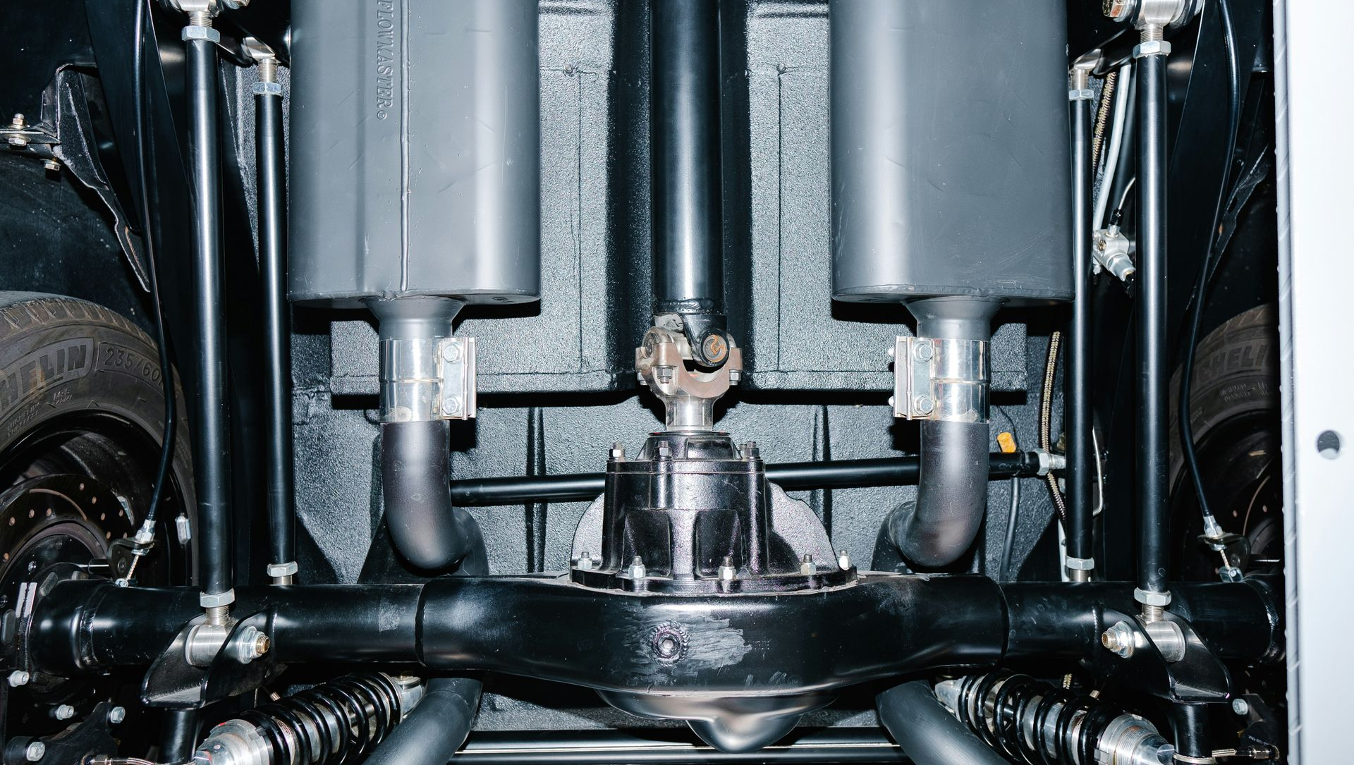 Close-up of a mechanical engine assembly with metal pistons, shafts, and pipes in a dark industrial setting