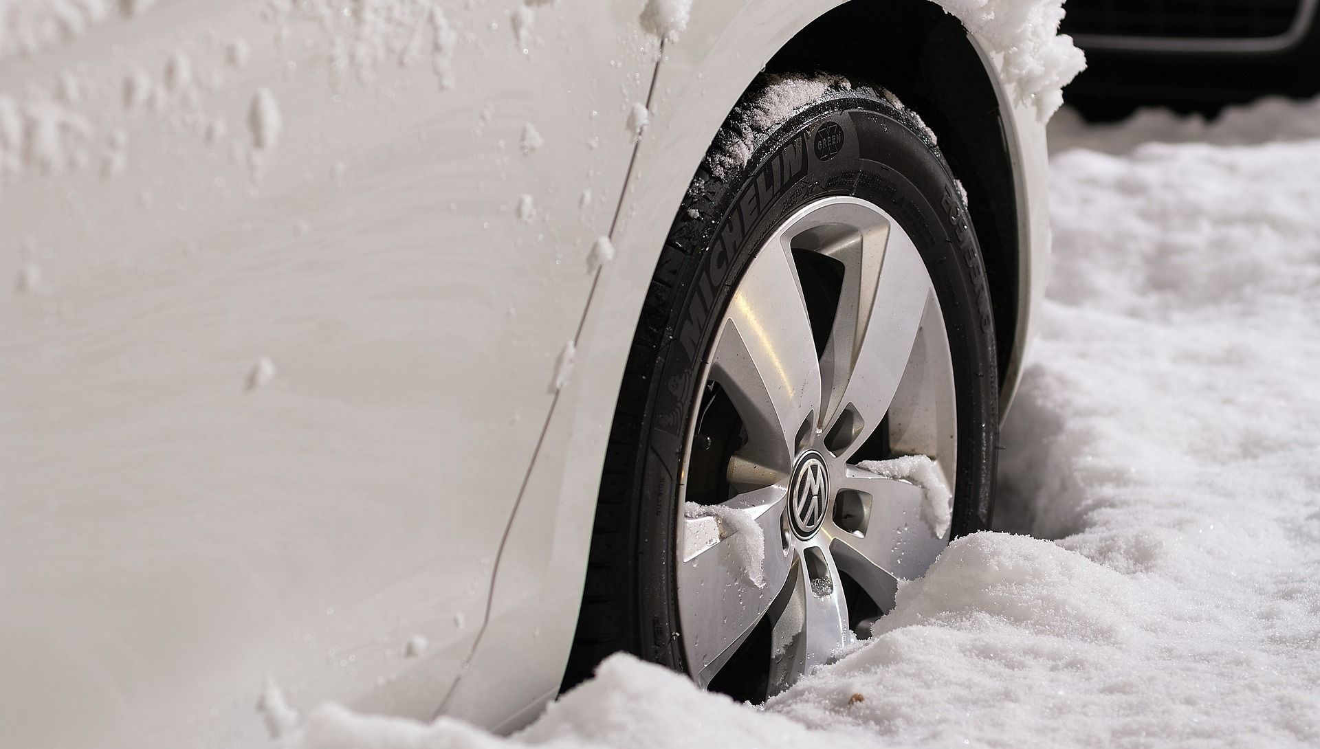 White car wheel stuck in deep snow.