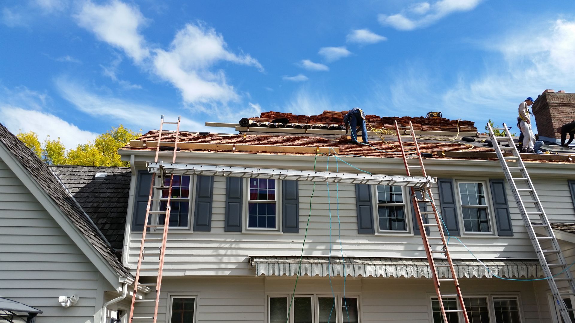 House roof severely damaged with exposed rafters and ladders during repair work