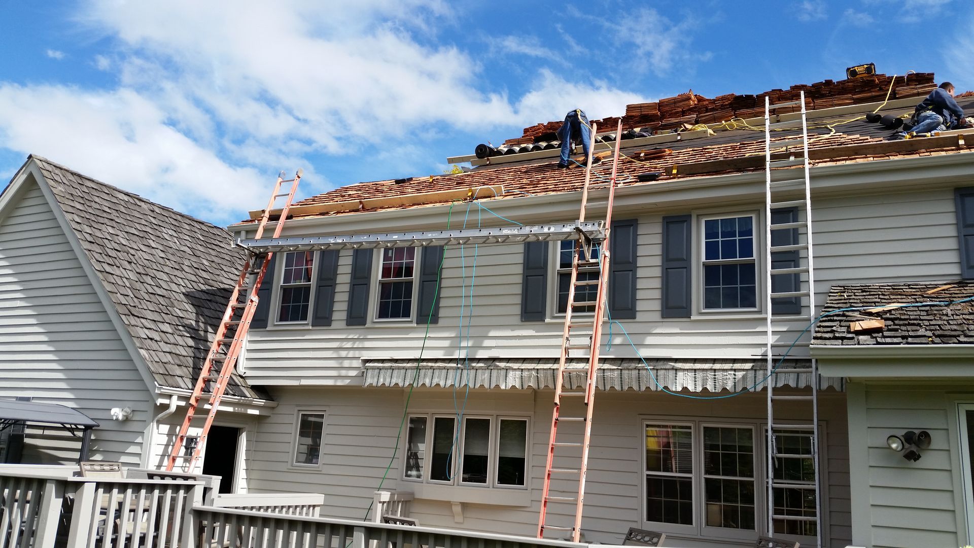 House roof under repair with ladders and workers on scaffolding