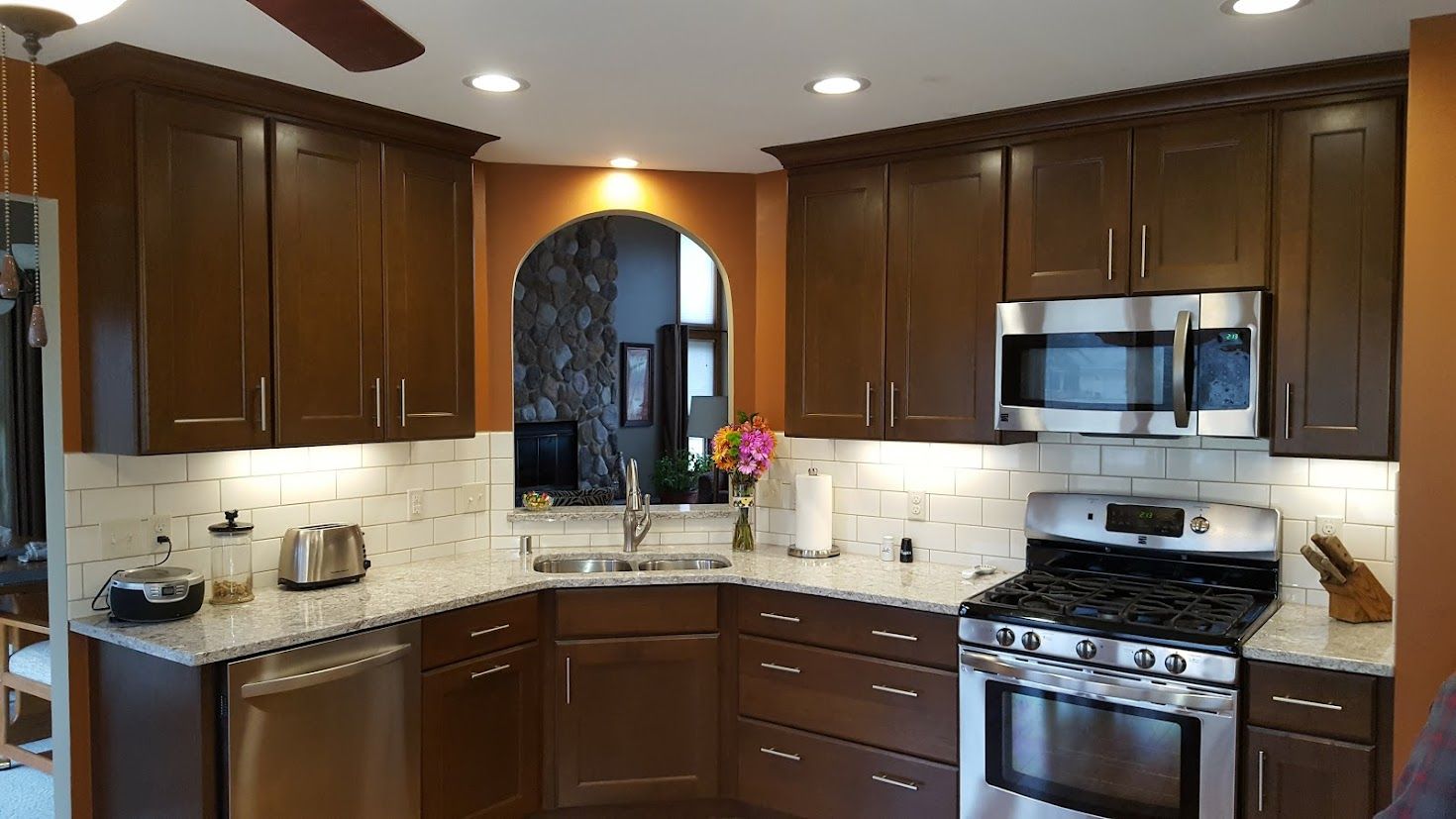 Modern kitchen with dark wood cabinets, stainless steel appliances, and a tiled backsplash around a sink and stove