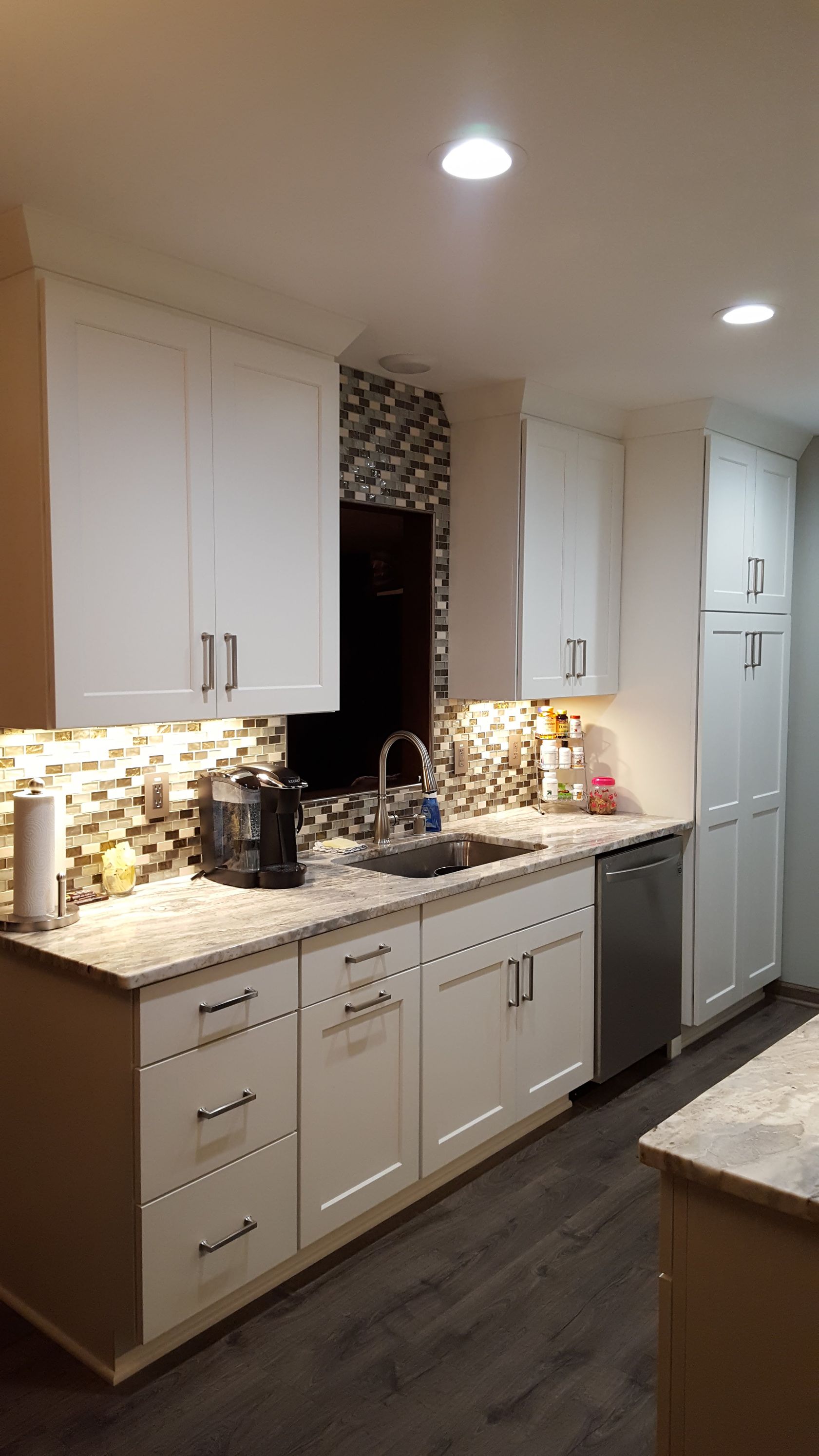 Modern kitchen with white cabinets, granite countertops, mosaic backsplash, and recessed ceiling lights