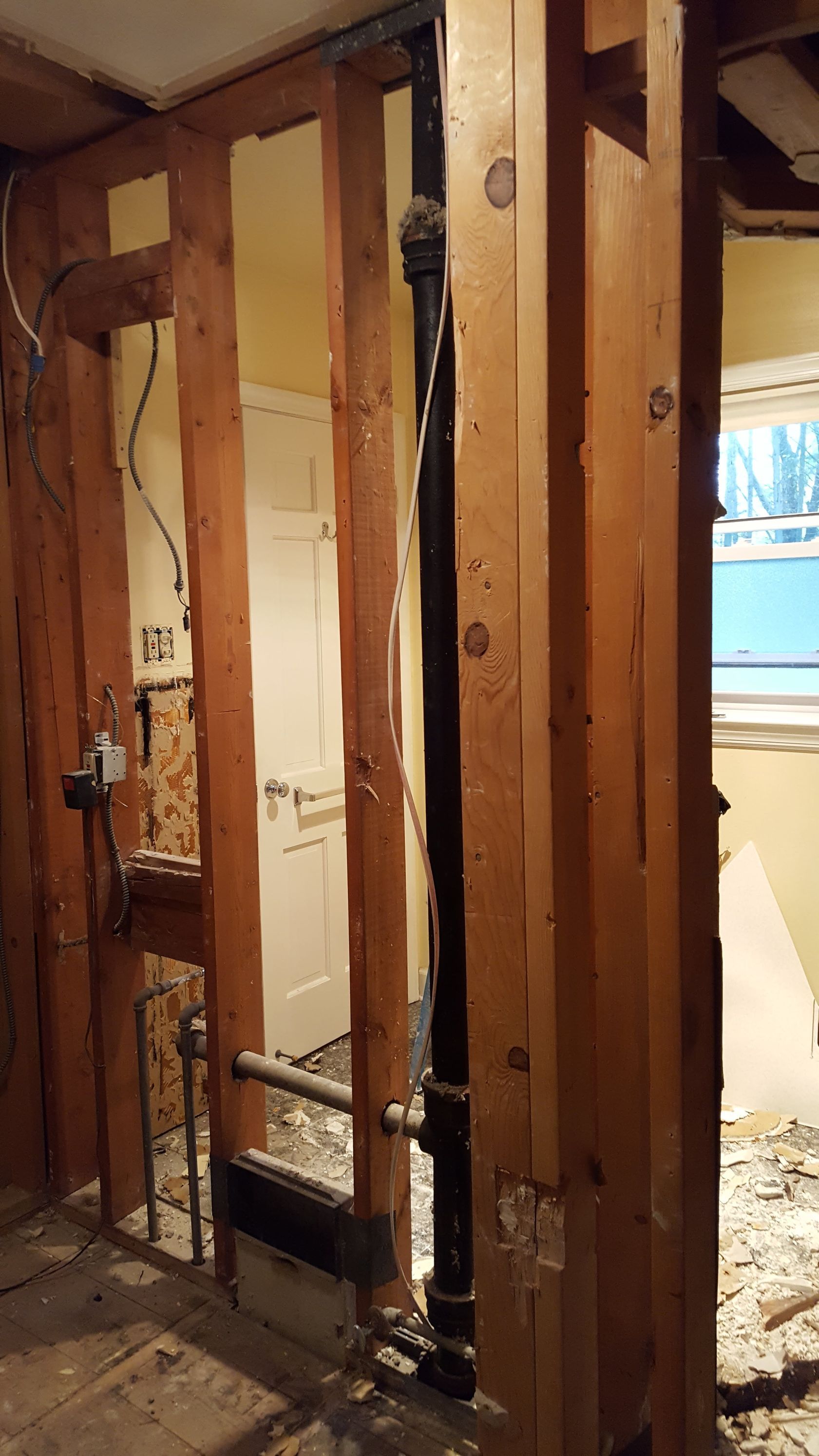 Interior wall framing and exposed plumbing in a partially demolished room during renovation