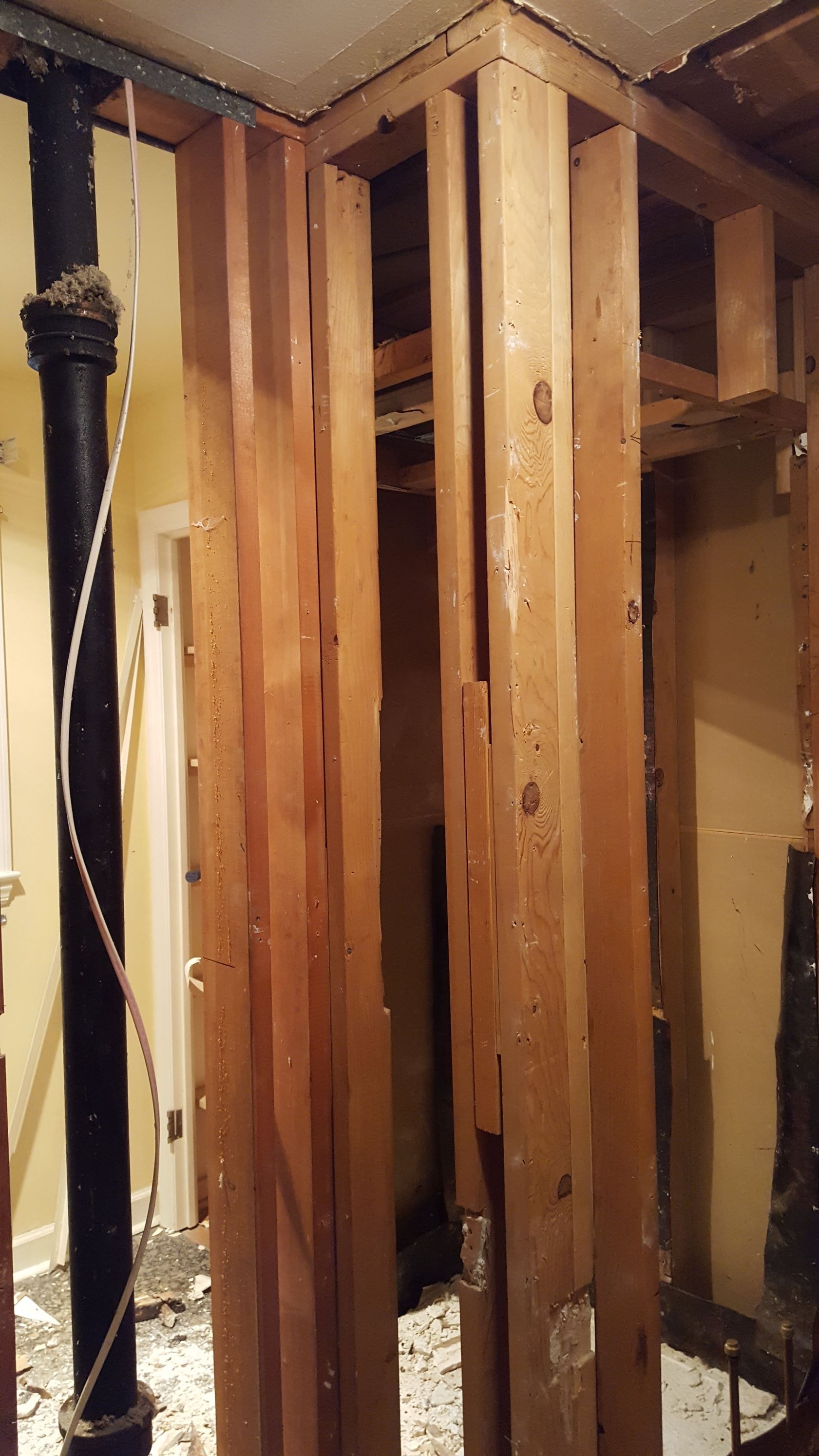 Exposed wooden wall framing in an unfinished interior room with visible studs and wiring.