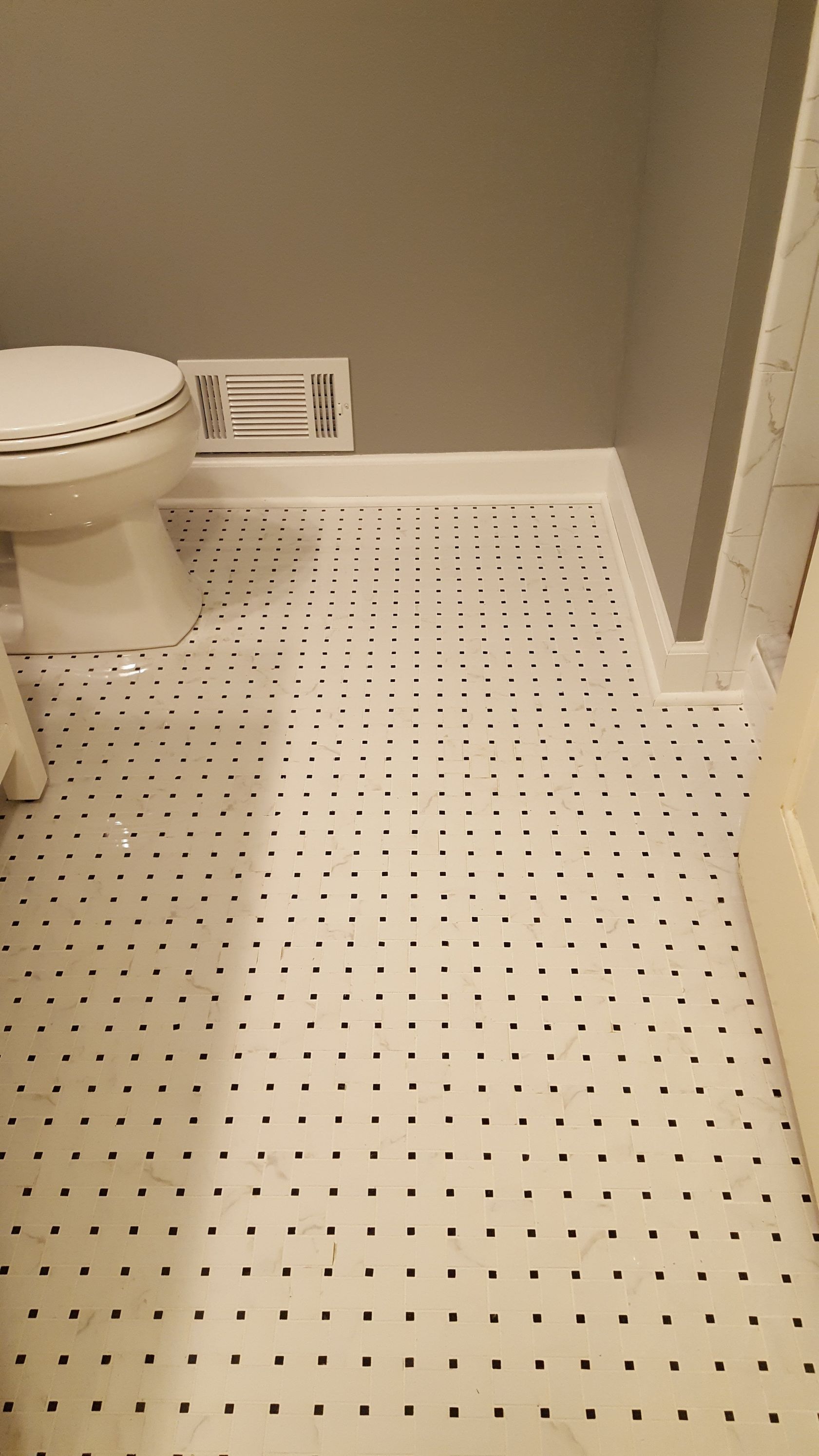 Small bathroom with white toilet, perforated white floor, and vent near the wall.