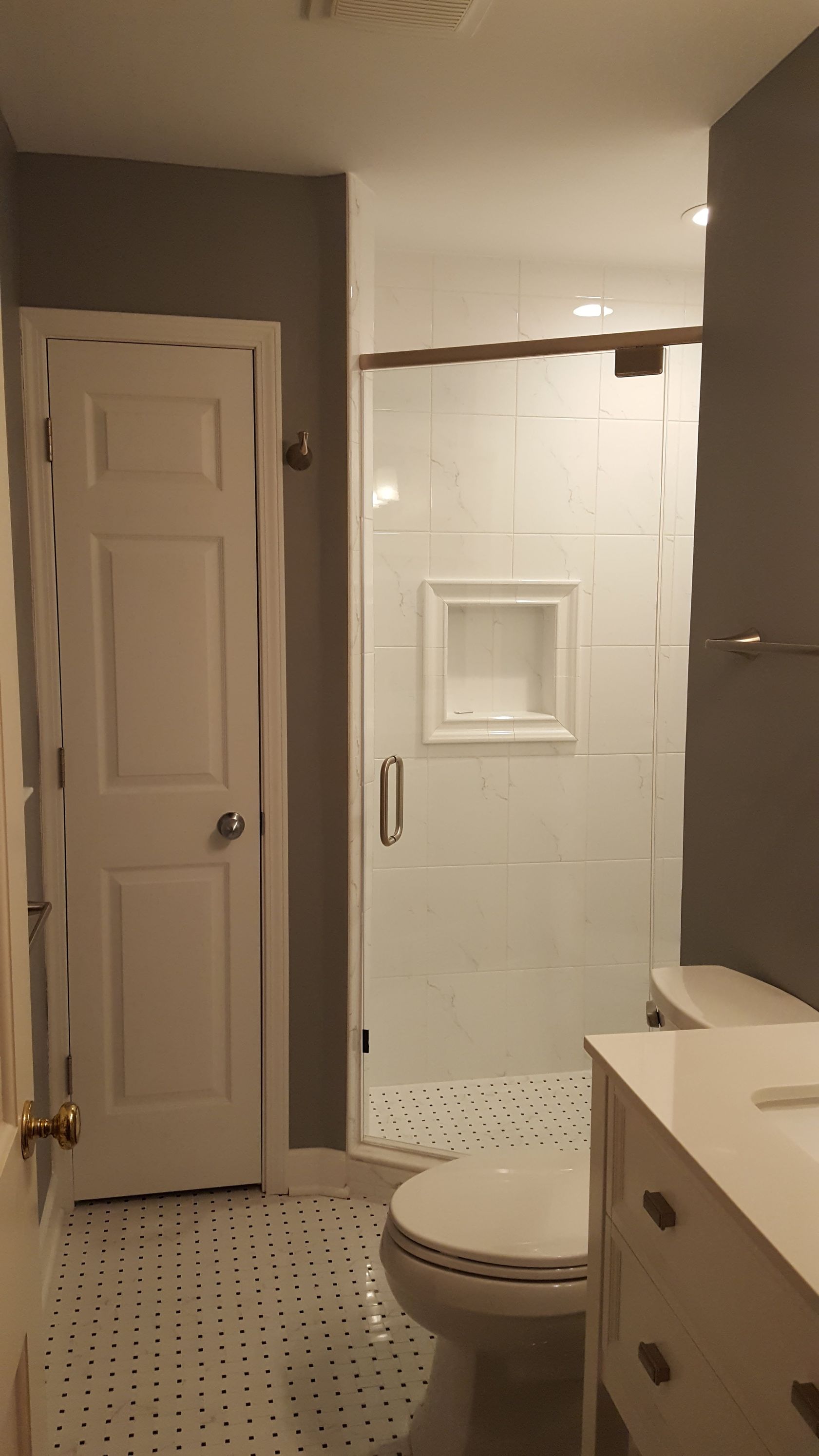 Small bathroom with toilet, shower stall, and vanity in gray tones