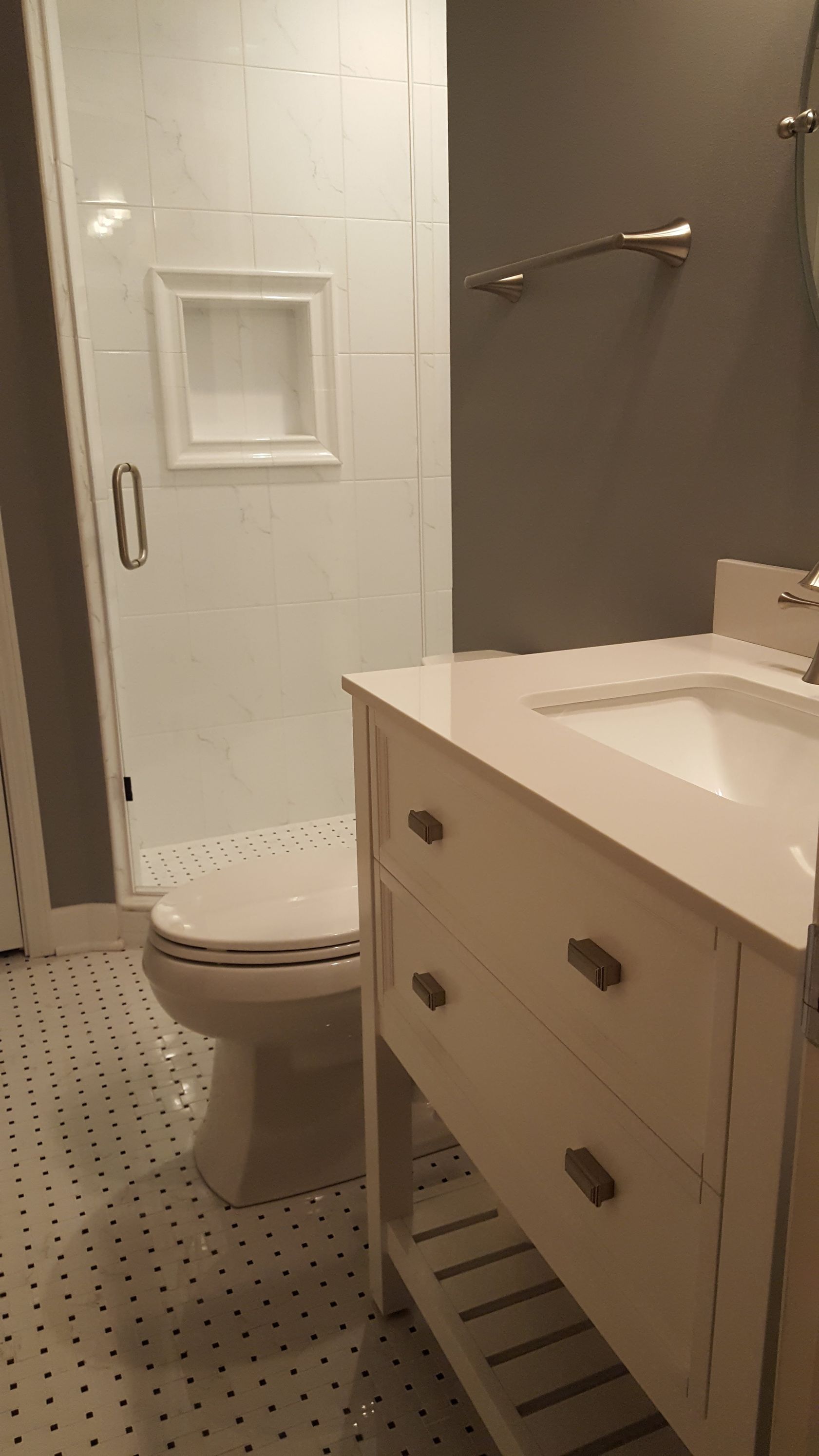 Compact bathroom with toilet, vanity sink, shower, and small mosaic tile floor.