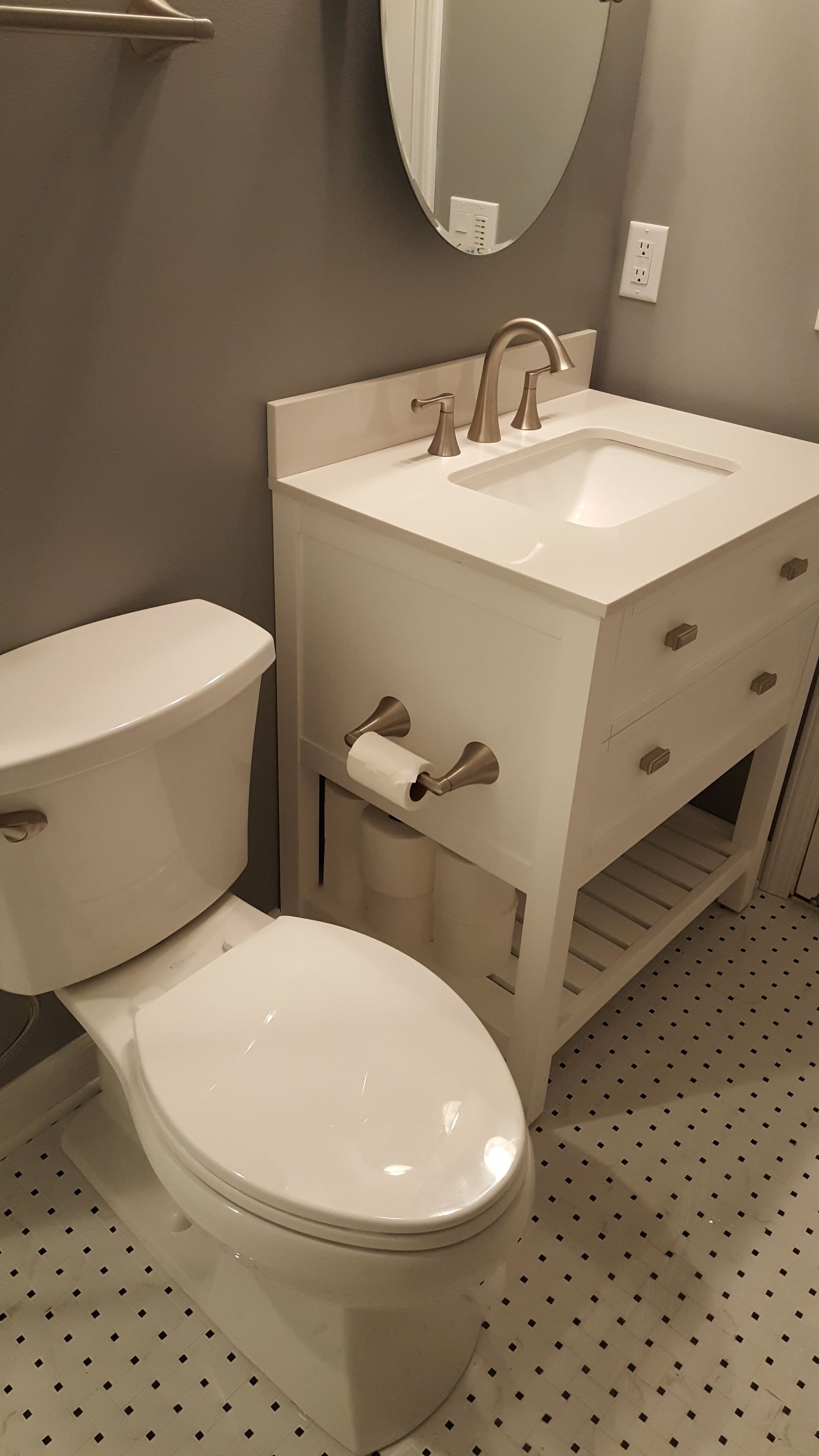 Small bathroom with white toilet, vanity sink, mirror, and beige walls.
