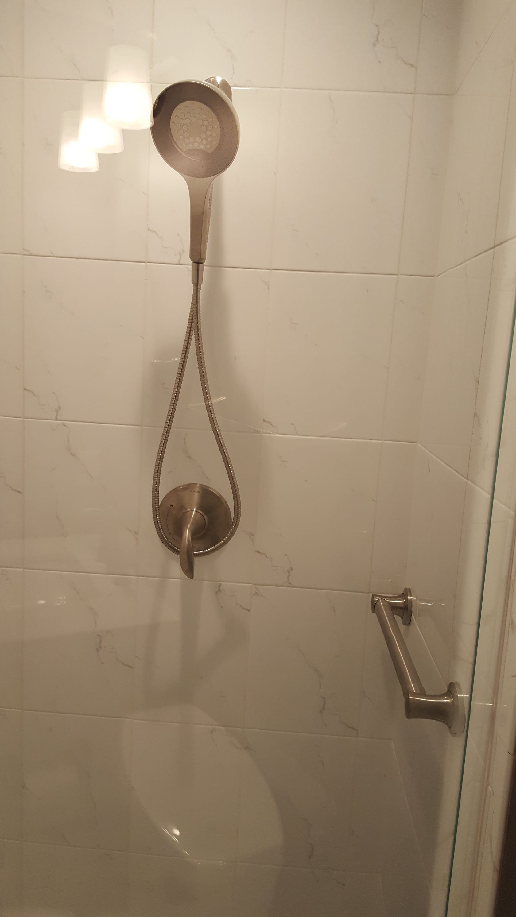 Shower wall with two metal drain covers connected by a chain and a small handle on the right.