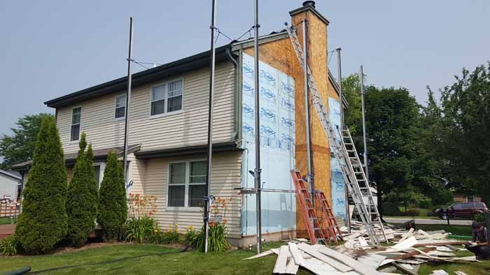 House exterior with ladders and siding work during renovation