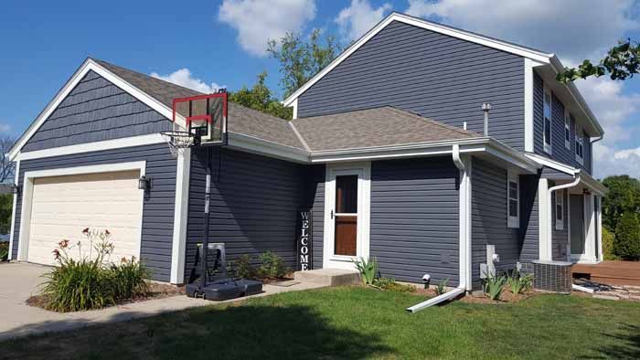 Suburban house with gray siding, attached garage, and a small basketball hoop by the driveway