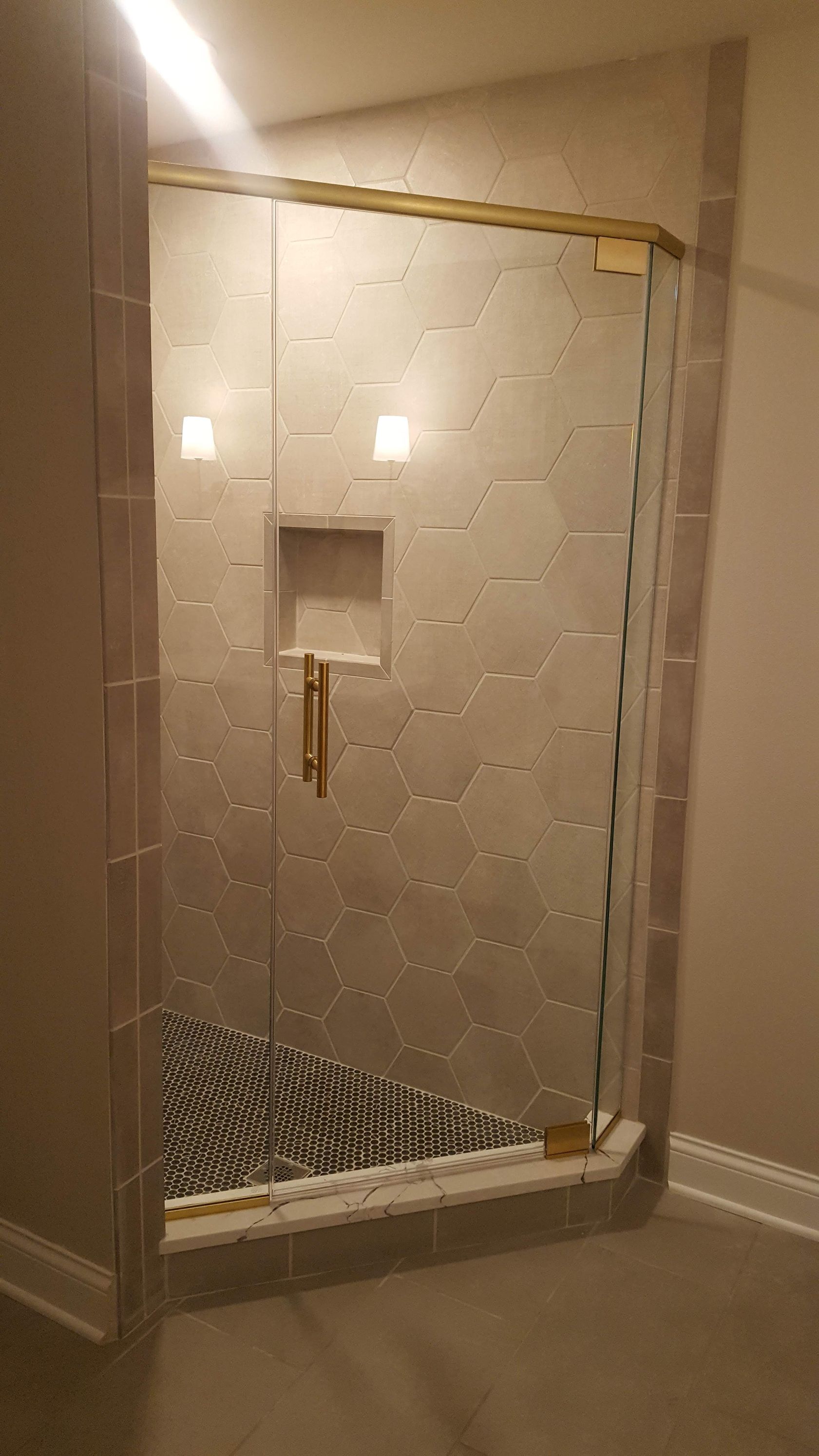 Glass shower enclosure with white tiled walls and a small recessed shelf in a bathroom