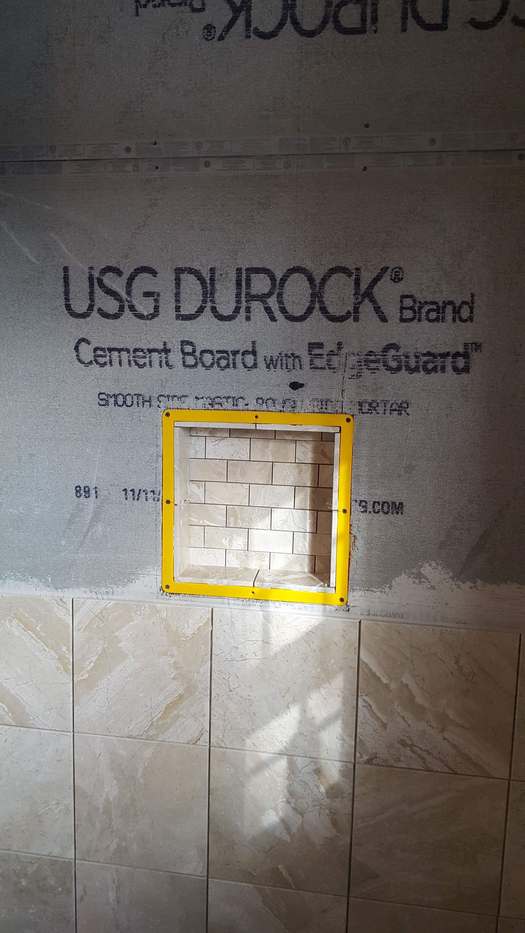USG Durock cement board wall with a small square opening outlined in yellow.