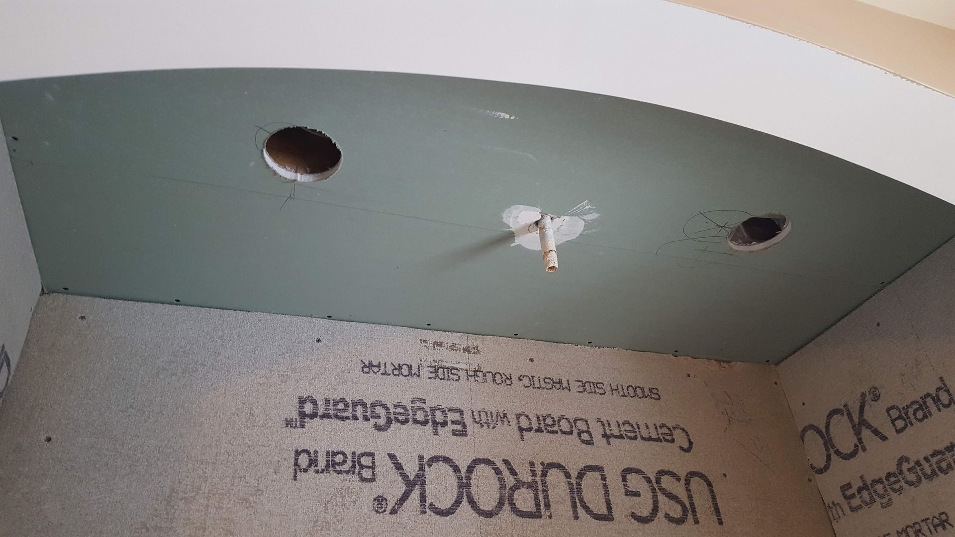 Ceiling with two recessed lights, a central wire, and partially finished drywall panels.