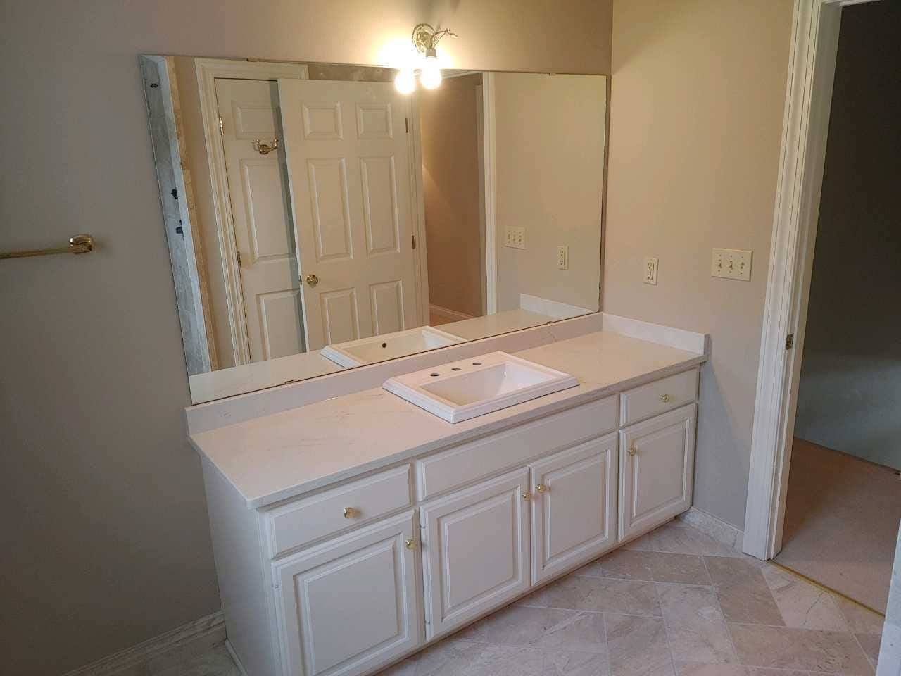 Bathroom vanity with double mirror, white cabinets, and beige walls