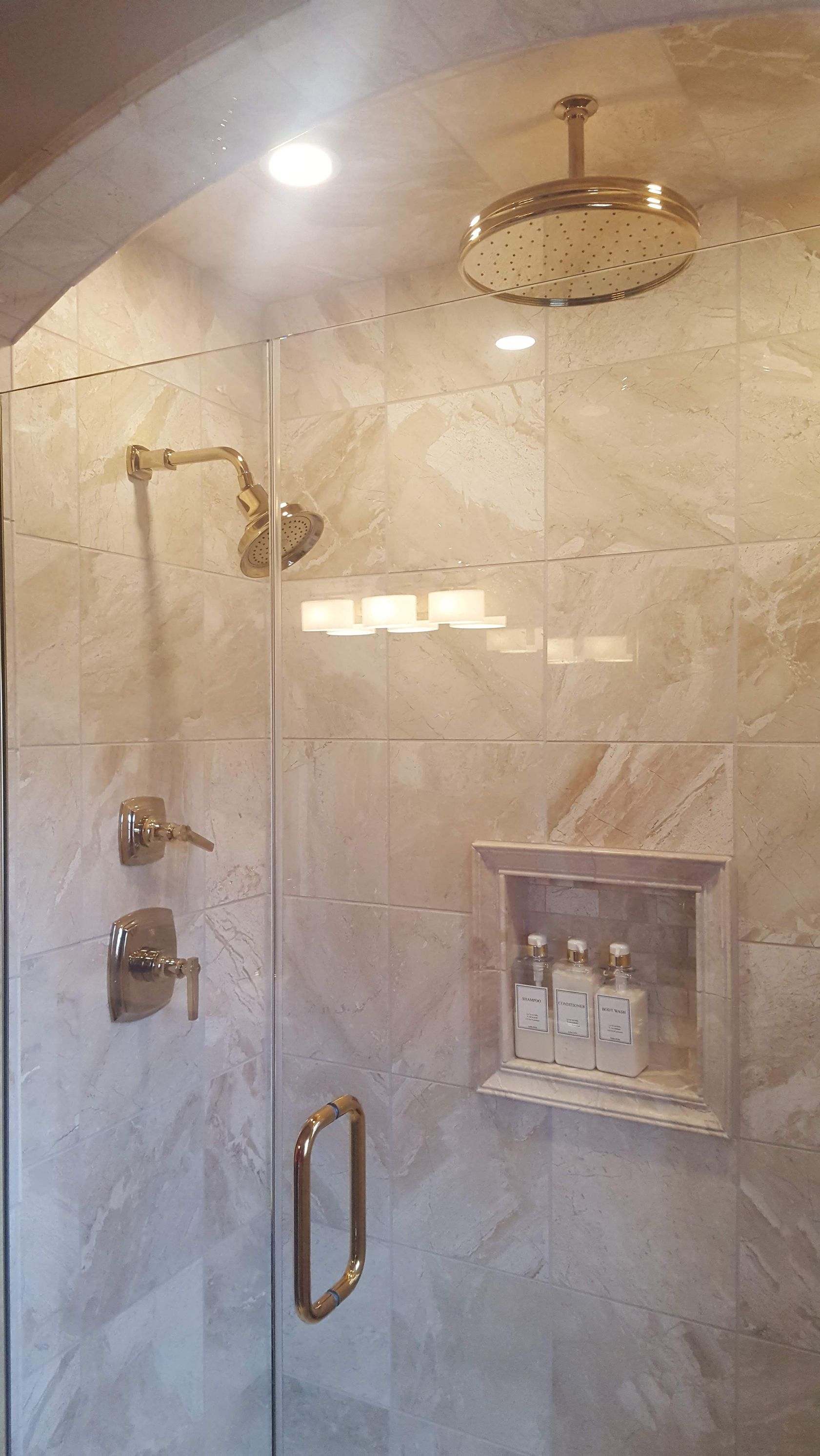 Marble-tiled walk-in shower with glass door, chrome fixtures, and a ceiling-mounted rain showerhead