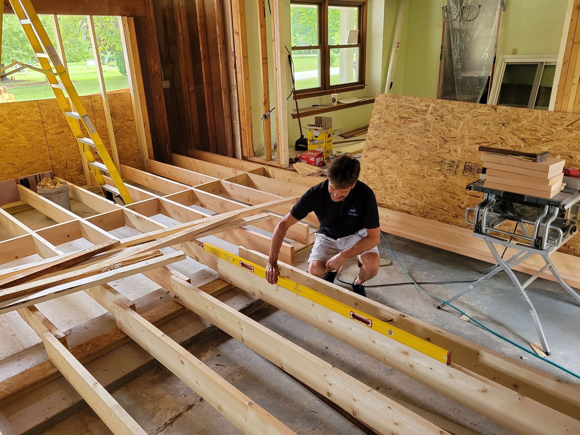 Worker measuring floor joists during home construction inside a partially framed room