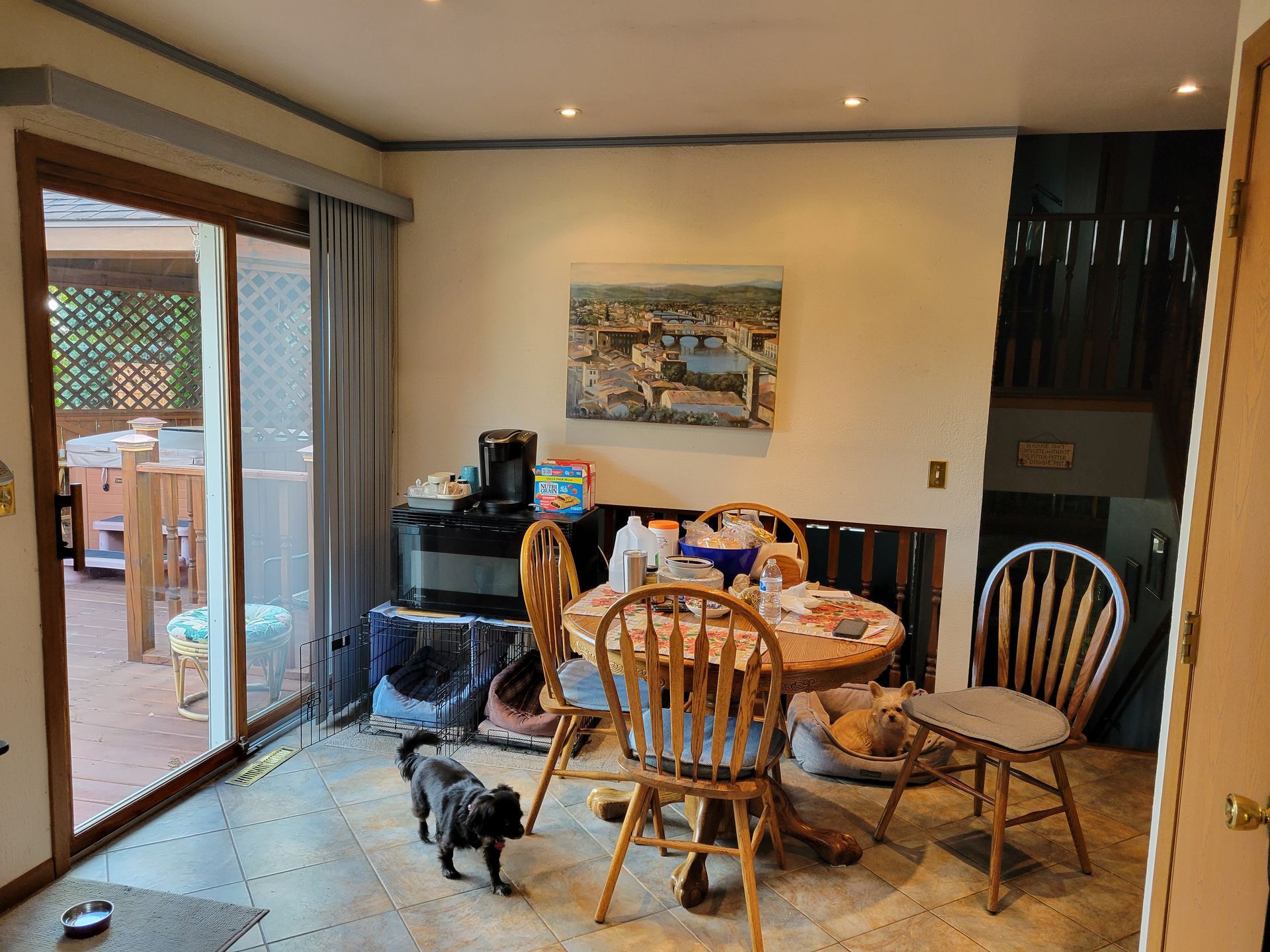 Dining room with a round table, chairs, and a small dog near a sliding glass door