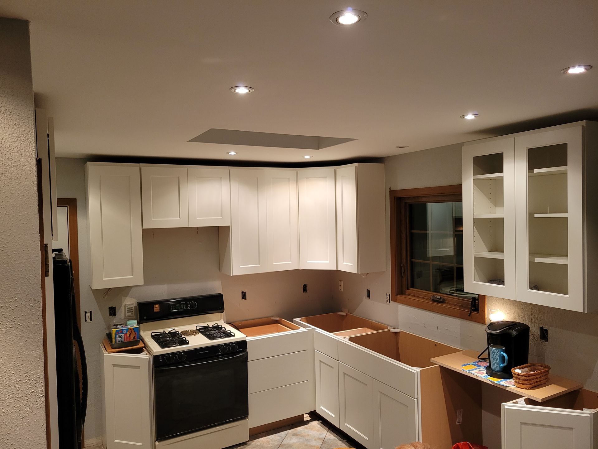 Modern kitchen with white cabinets, black stove, and recessed ceiling lights