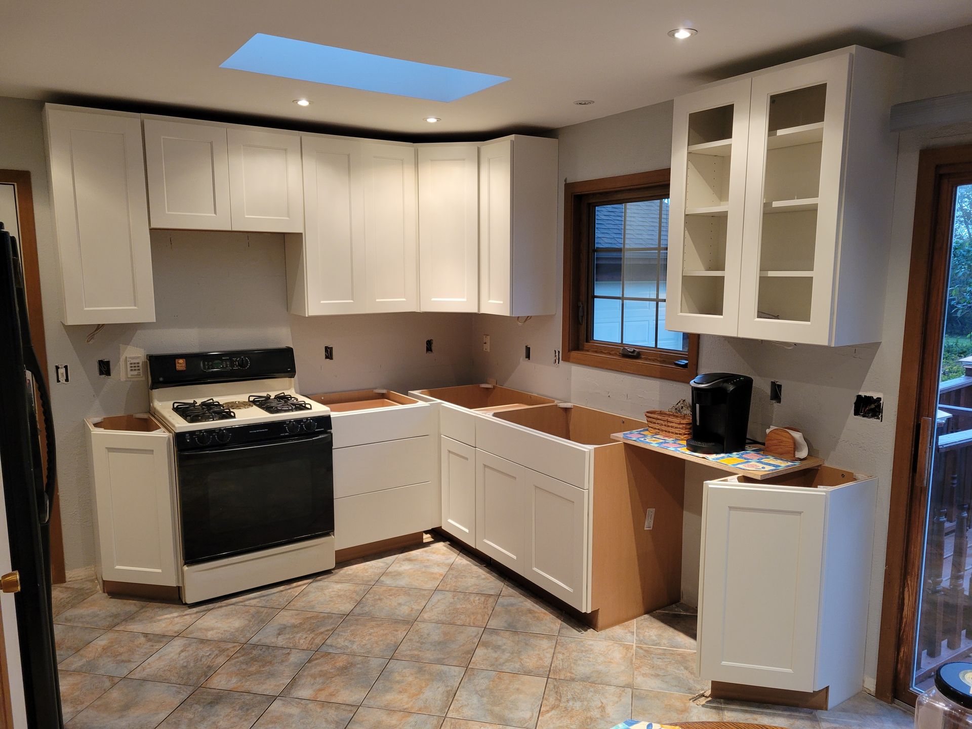 Kitchen with white cabinets, black stove, wood countertops, and a skylight