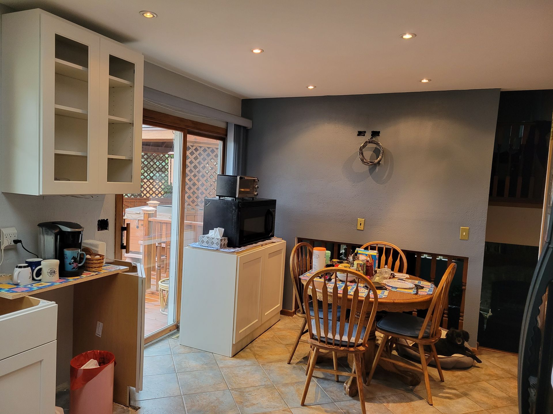 Kitchen-dining room with round table, wooden chairs, cabinets, and glass doors to a patio.