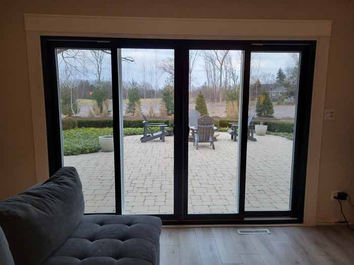 Living room with dark sofa facing large sliding glass doors to a patio and garden view