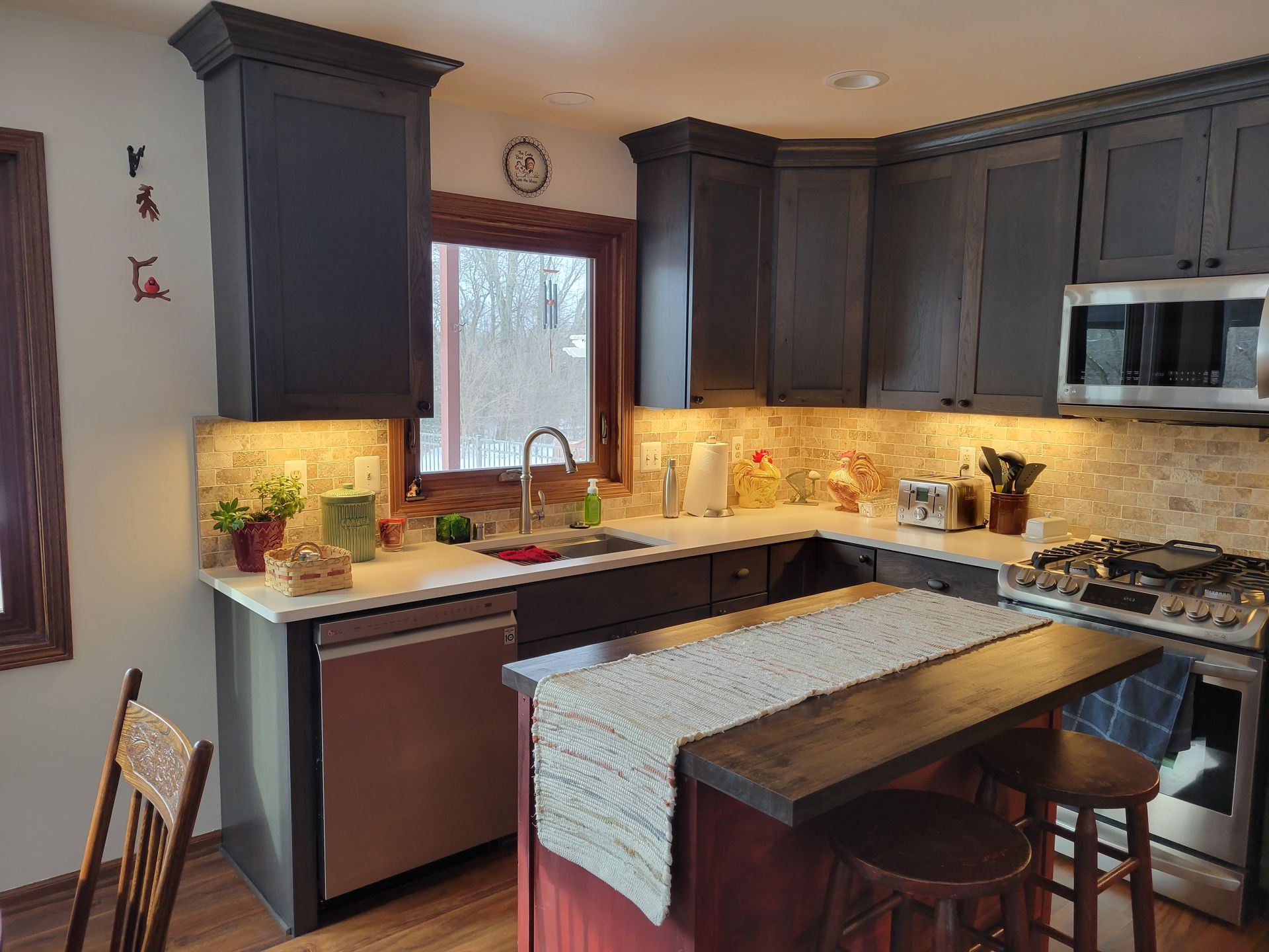 Modern kitchen with gray cabinets, granite island, stainless appliances, and a window over the sink