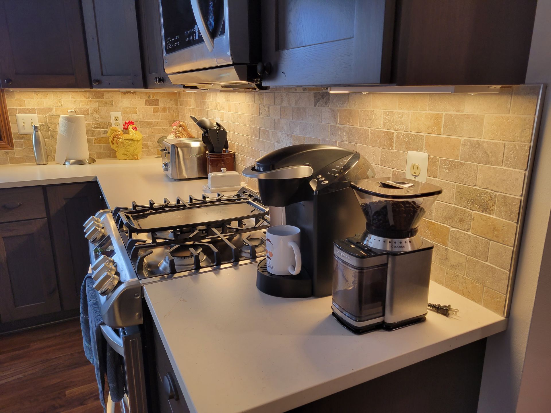 Modern kitchen counter with gas stove, coffee maker, and blender under warm under-cabinet lighting