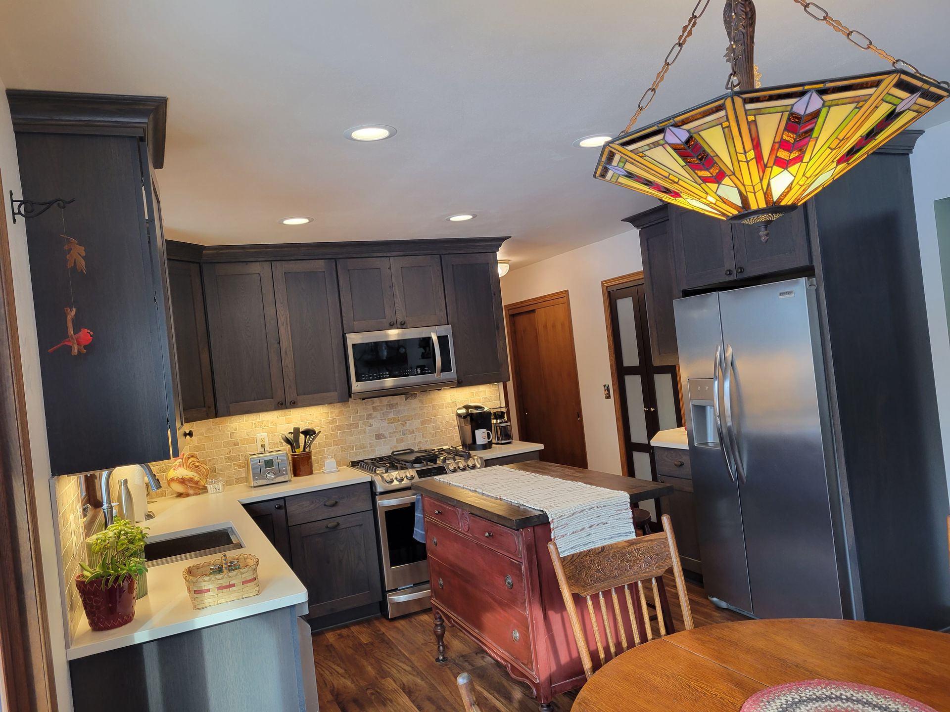 Modern kitchen with dark cabinets, stainless appliances, island, and stained-glass pendant light