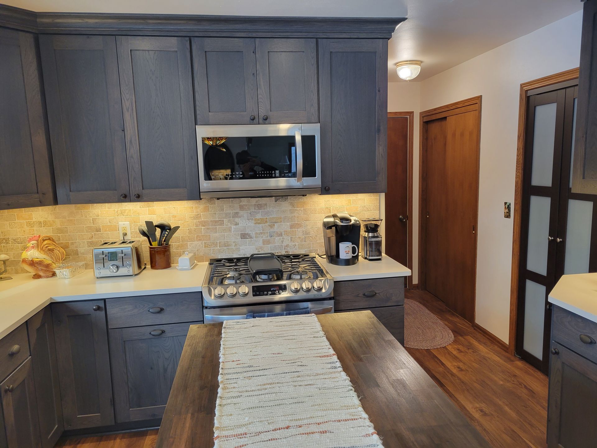 Modern kitchen with dark cabinets, stainless steel appliances, and a wooden island countertop.