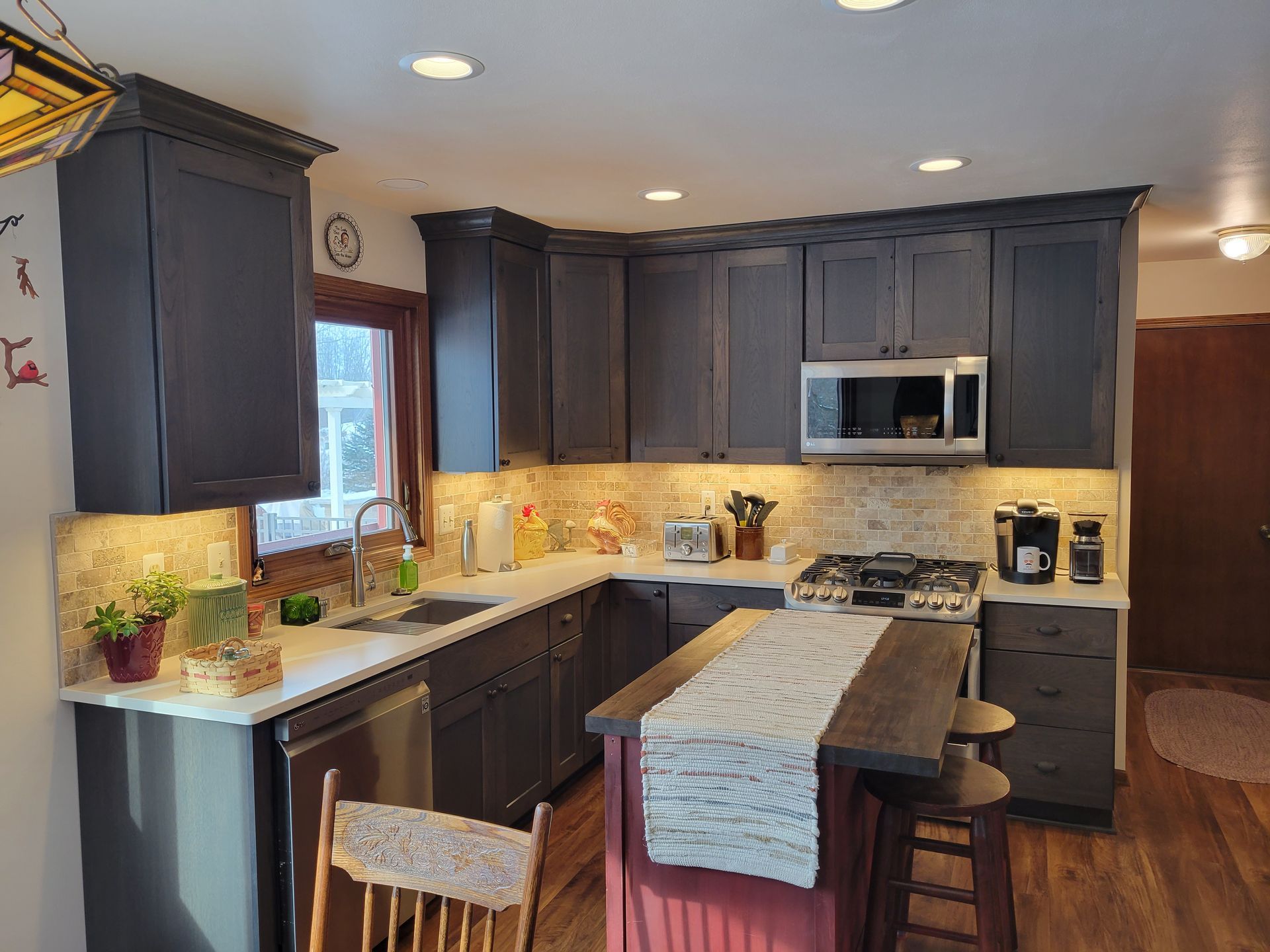 Modern kitchen with dark cabinets, granite island, barstools, and stainless steel appliances