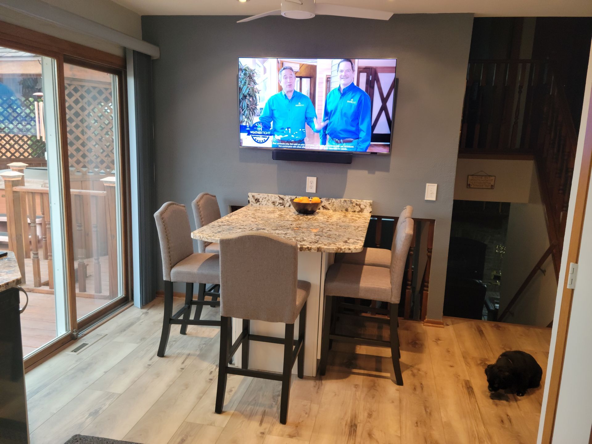 Dining room with wall-mounted TV, table set for four, and sliding glass door to a deck.