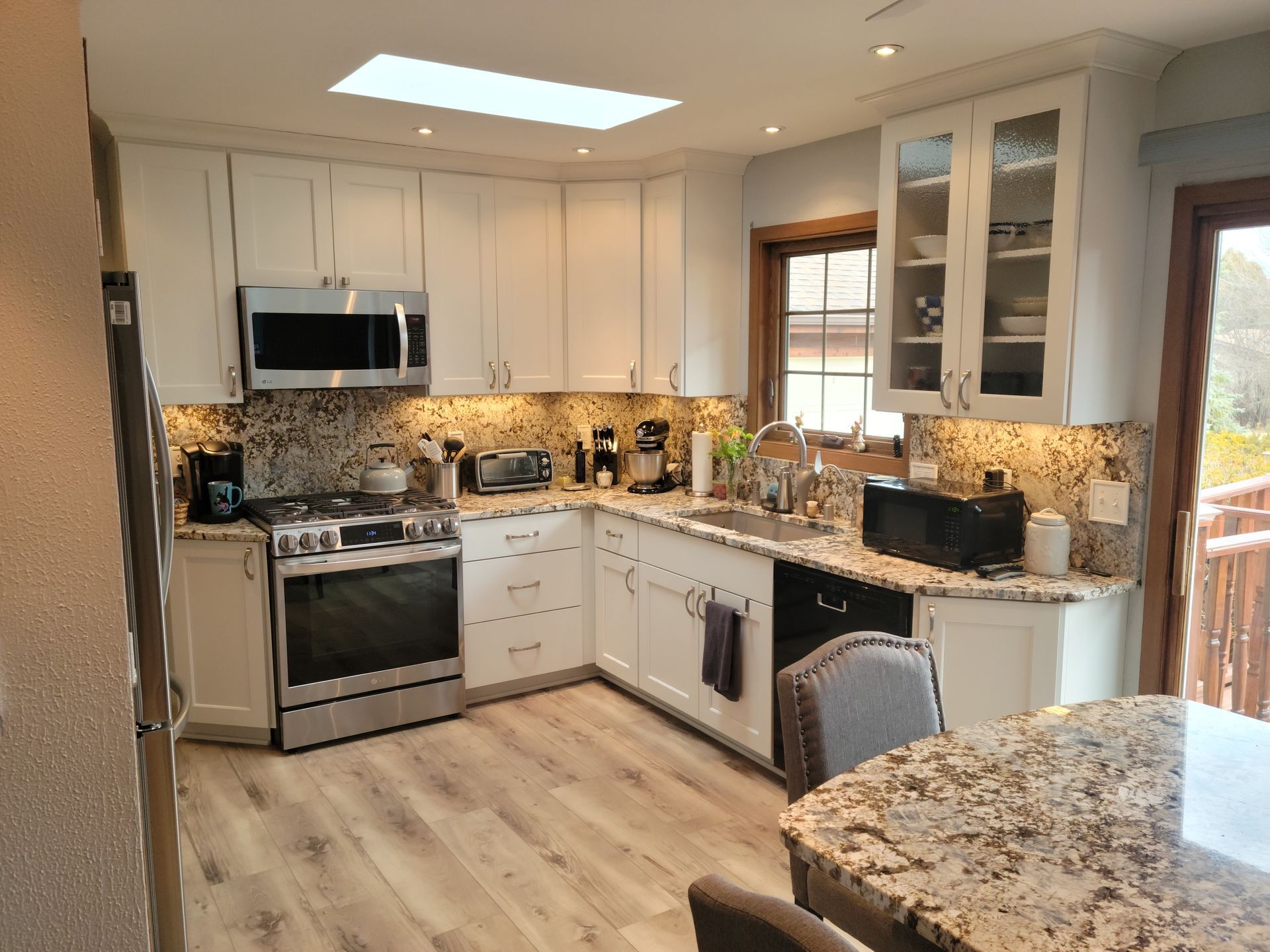 Bright modern kitchen with white cabinets, stainless appliances, and granite countertops