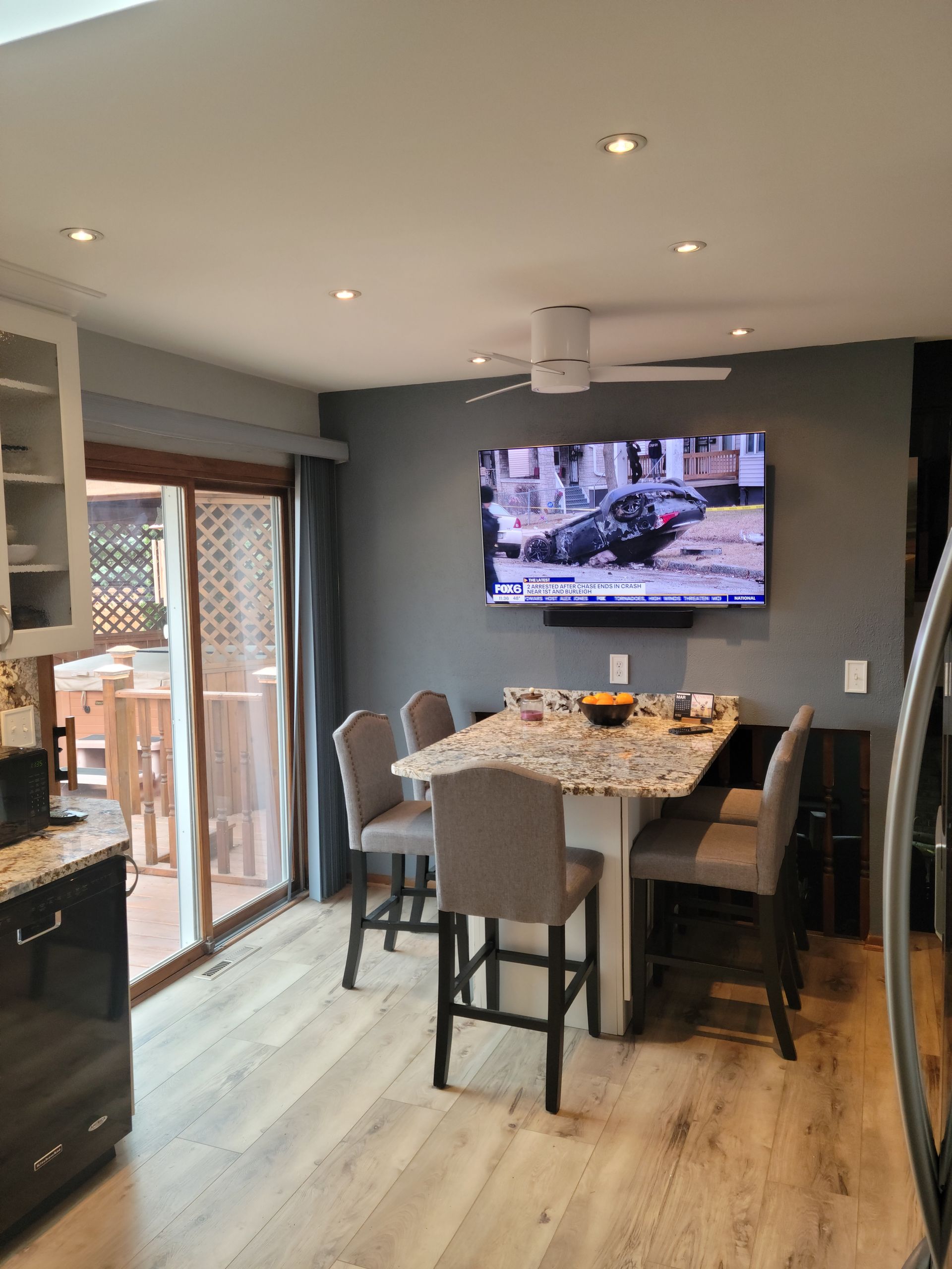 Modern dining area with a table, four chairs, wall TV, and sliding glass door to a patio.