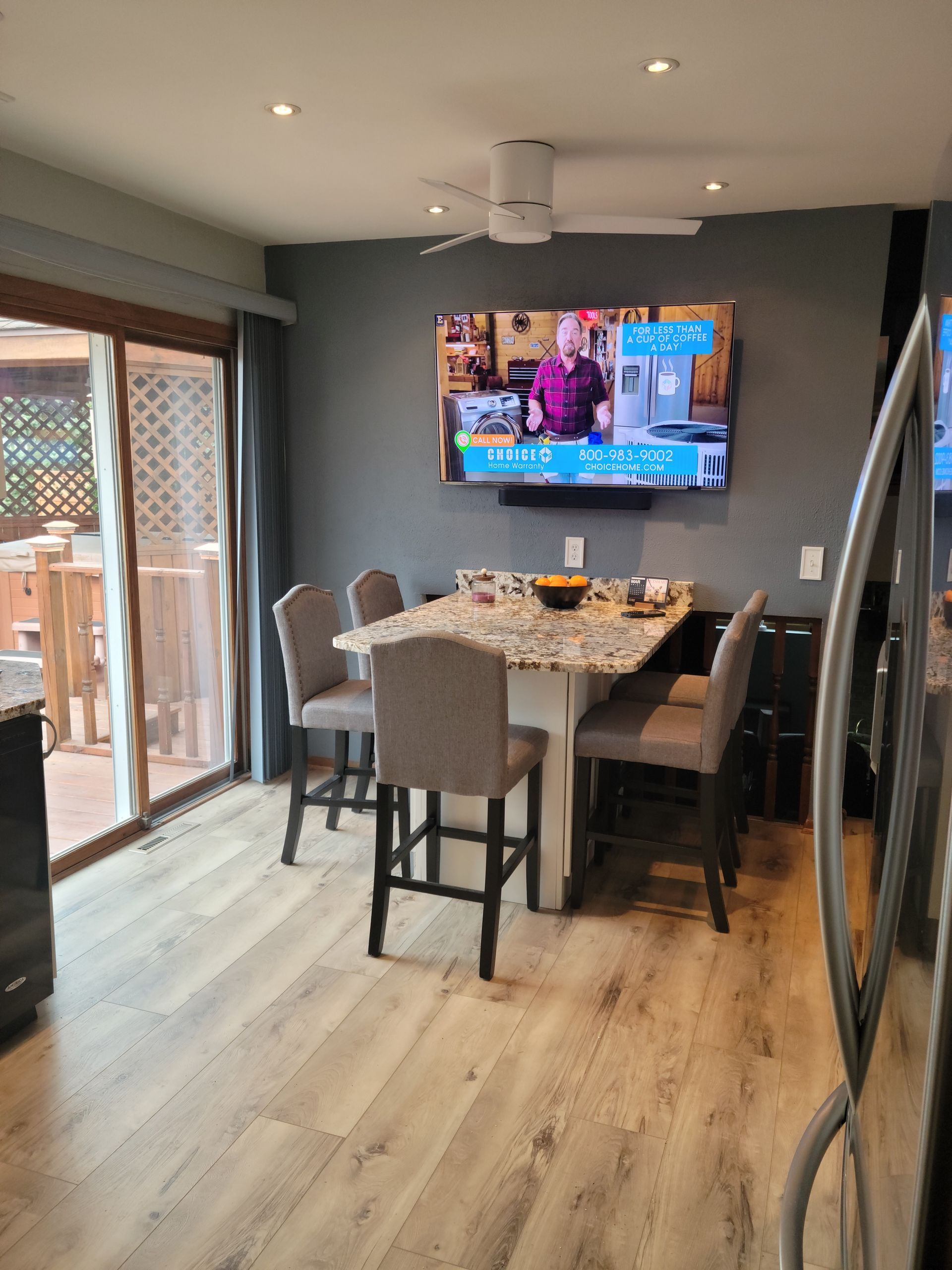 Modern dining room with table set for a meal, wall-mounted TV, and sliding glass door to a deck