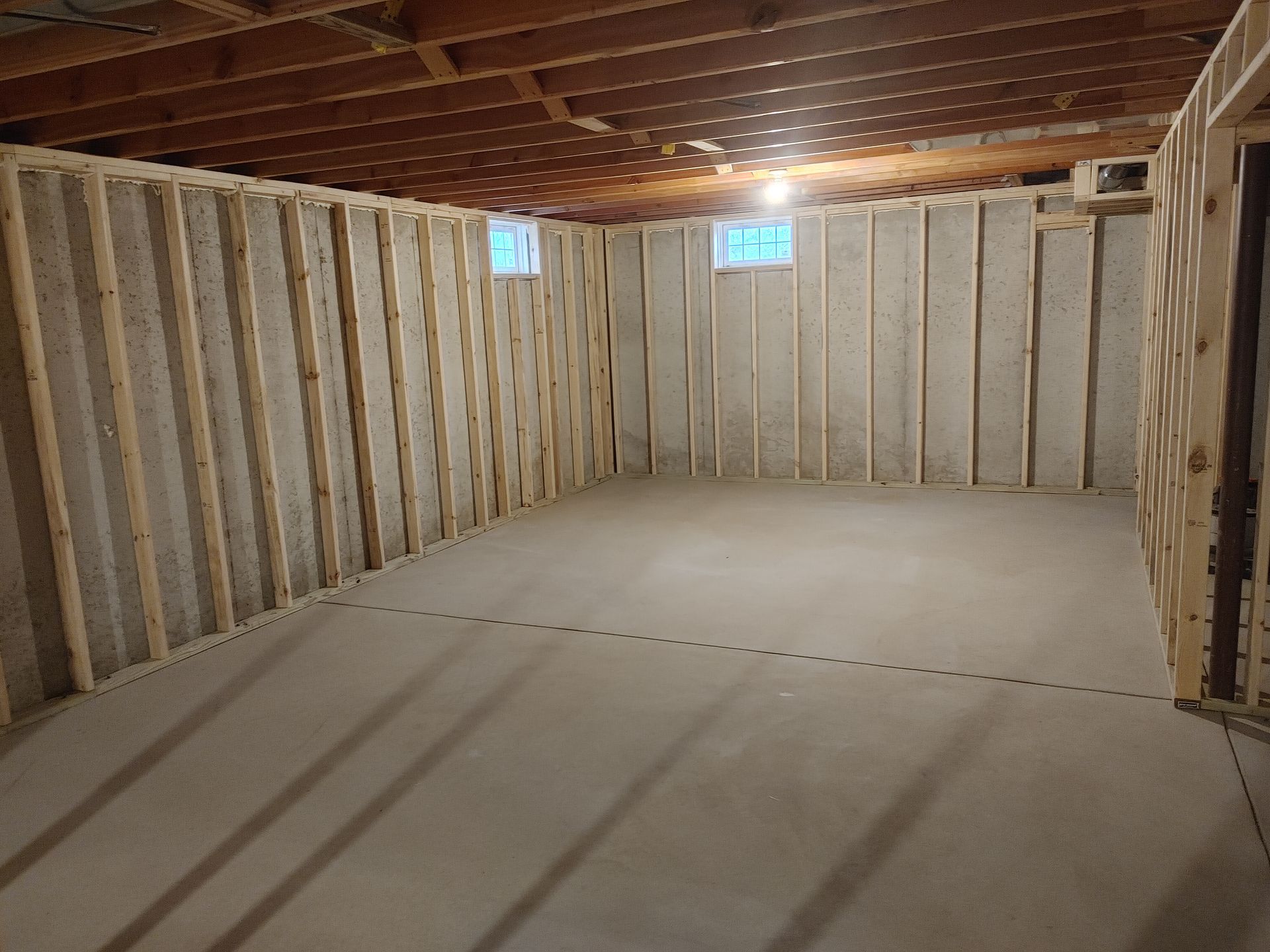 Unfinished basement interior with exposed studs, wood ceiling, and concrete floor under construction