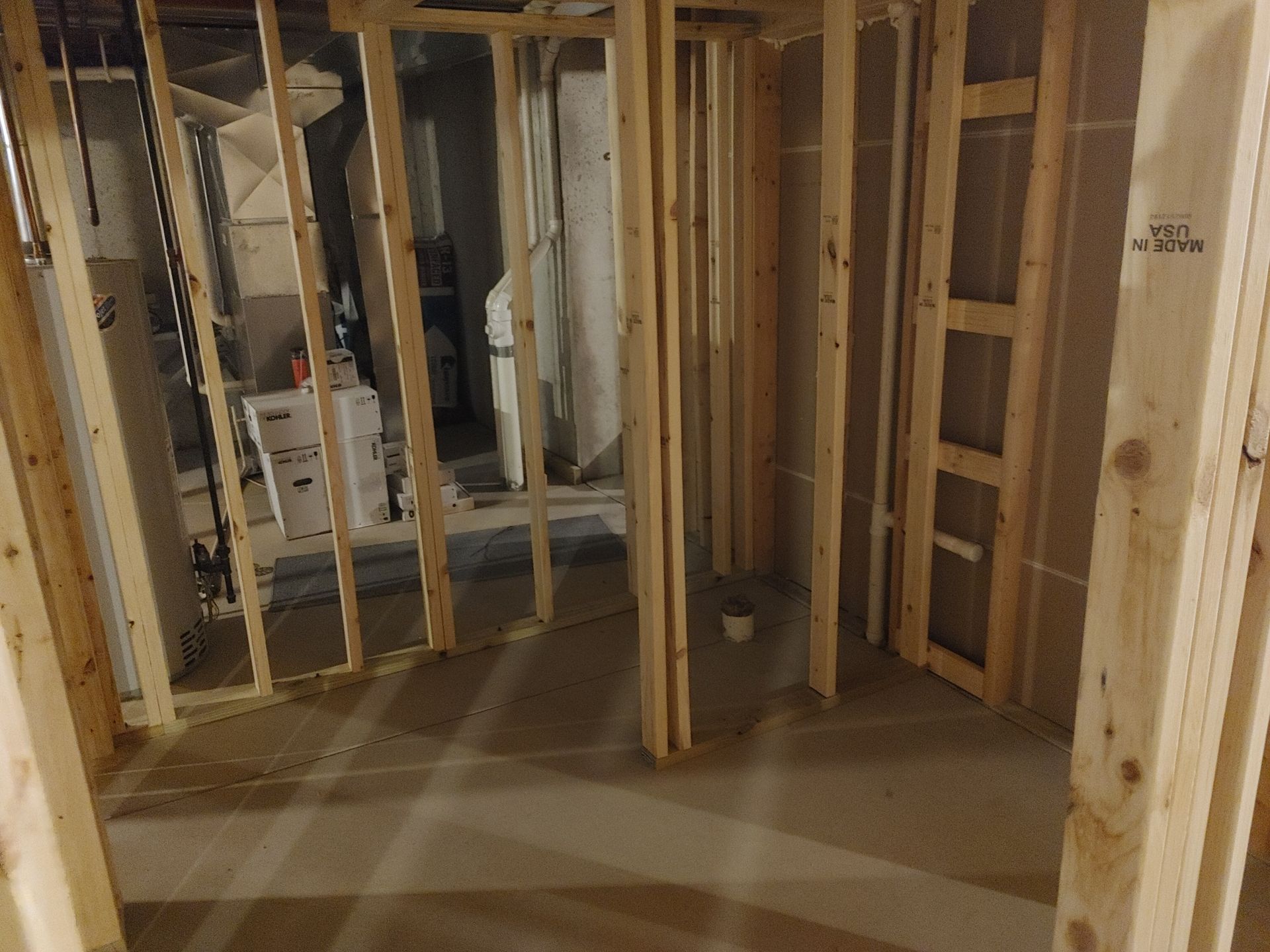 Unfinished basement with exposed wooden studs and a concrete floor in a framed interior space