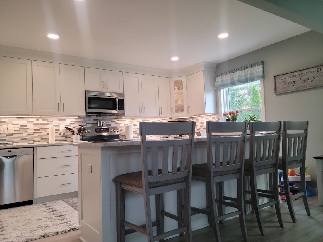 Bright modern kitchen with white cabinets, island seating, and tiled backsplash