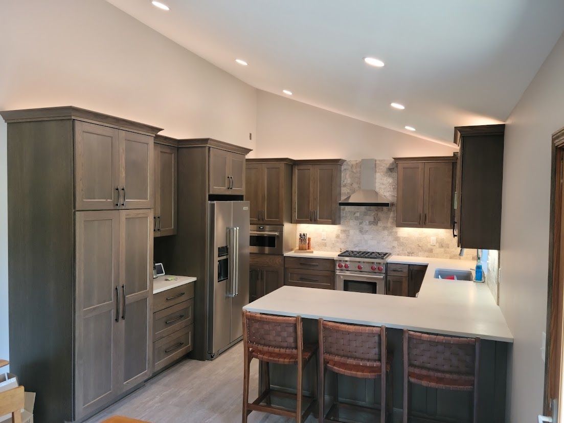 Modern kitchen with gray cabinets, white countertops, stainless appliances, and a central island with stools