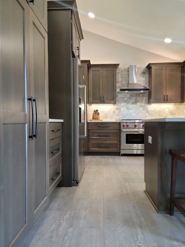 Modern kitchen with gray cabinets, stainless steel appliances, and a light wood floor