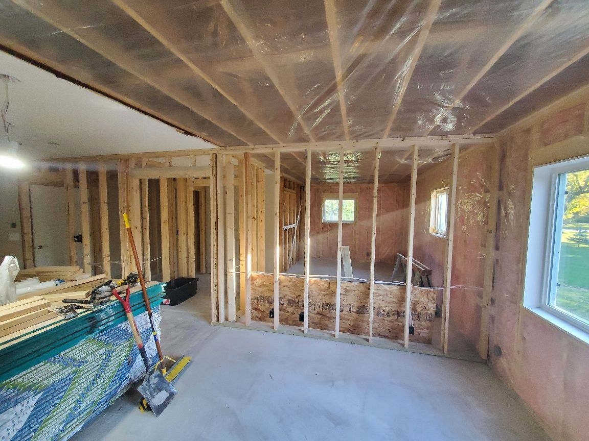 Unfinished room with exposed studs, insulation, and tools on the floor.