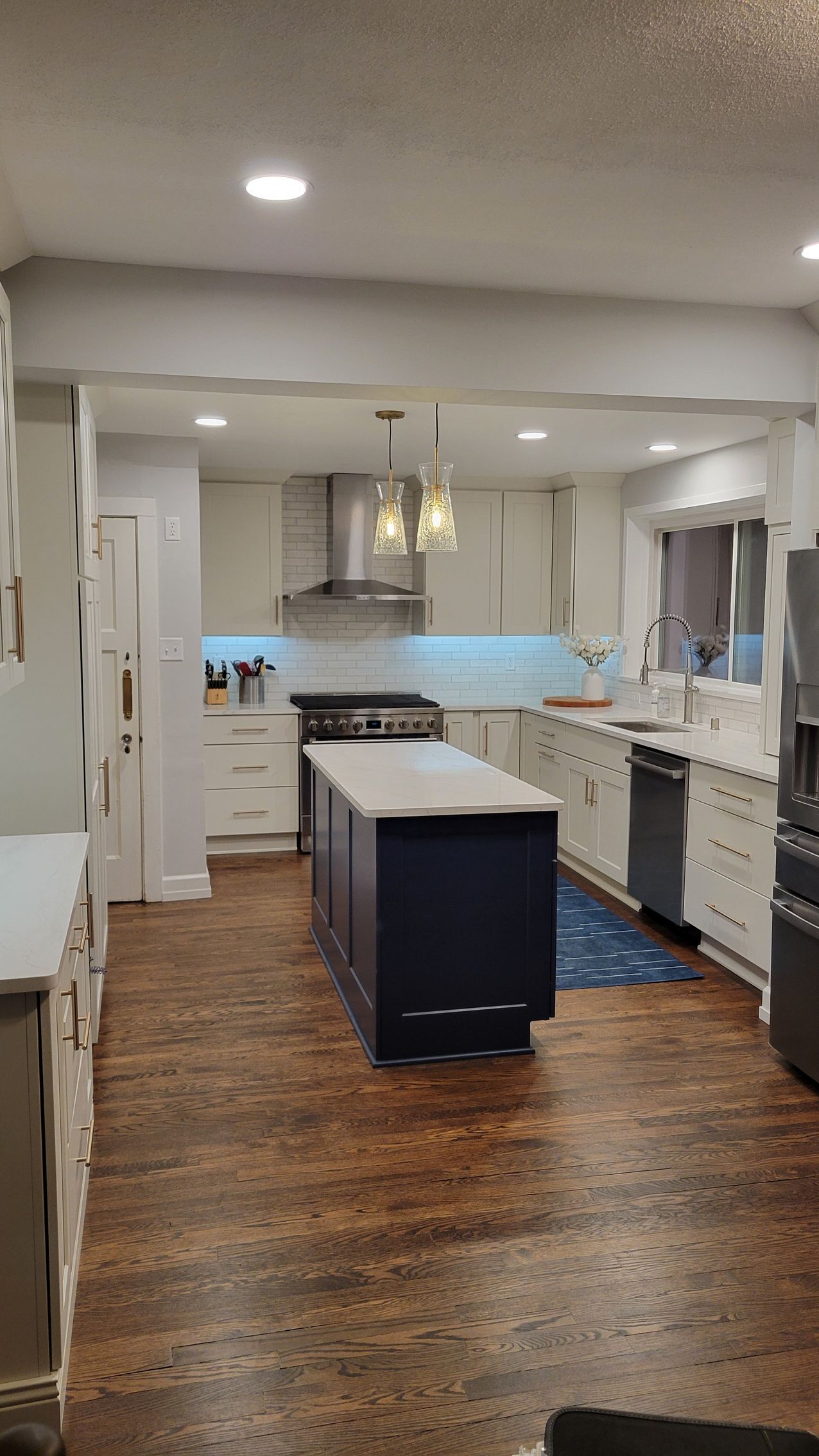 Bright modern kitchen with white cabinets, a navy island, and wood floors