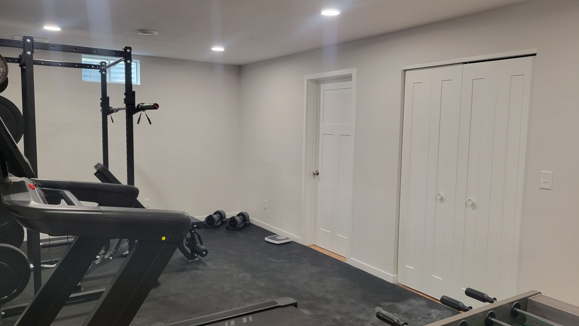 Home gym with treadmill and weight rack beside white double closet doors and a single door