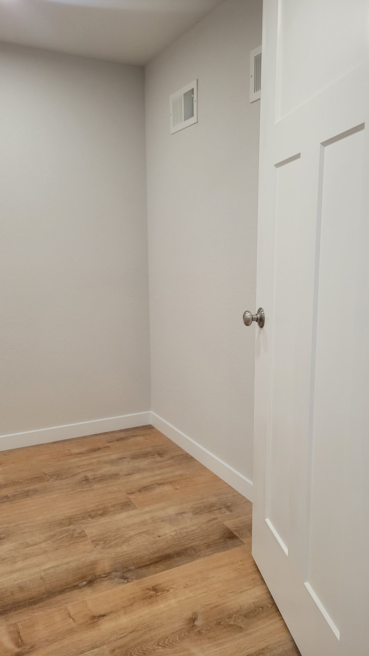 Empty white room with hardwood floor and closed closet doors