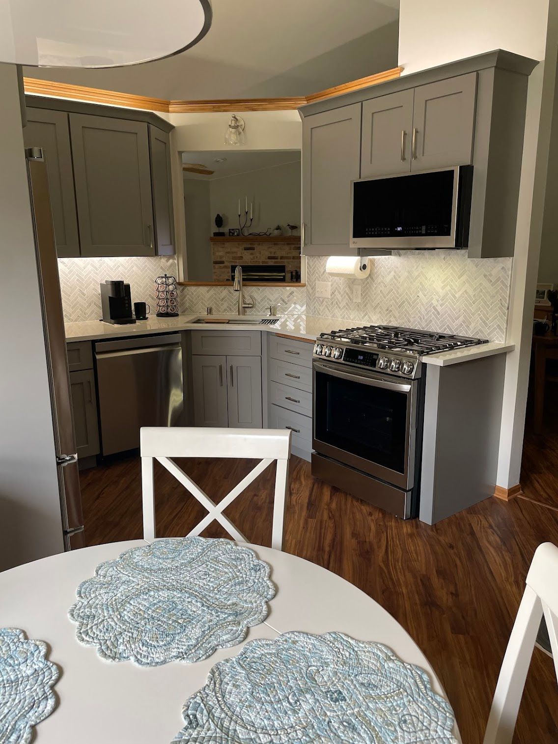 Modern kitchen with gray cabinets, stainless appliances, and round dining table in foreground