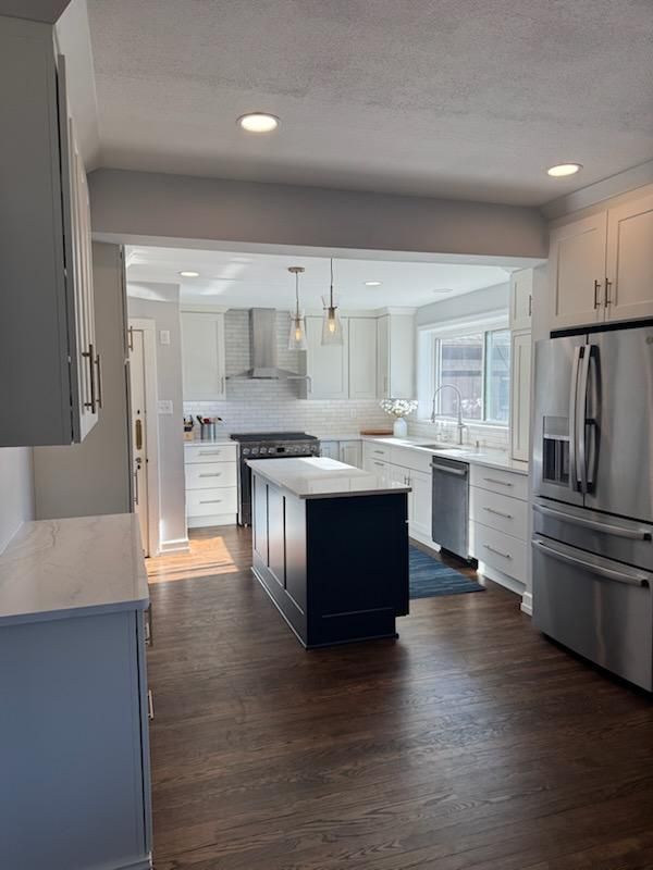 Bright modern kitchen with white cabinets, dark wood floors, and a blue island centerpiece