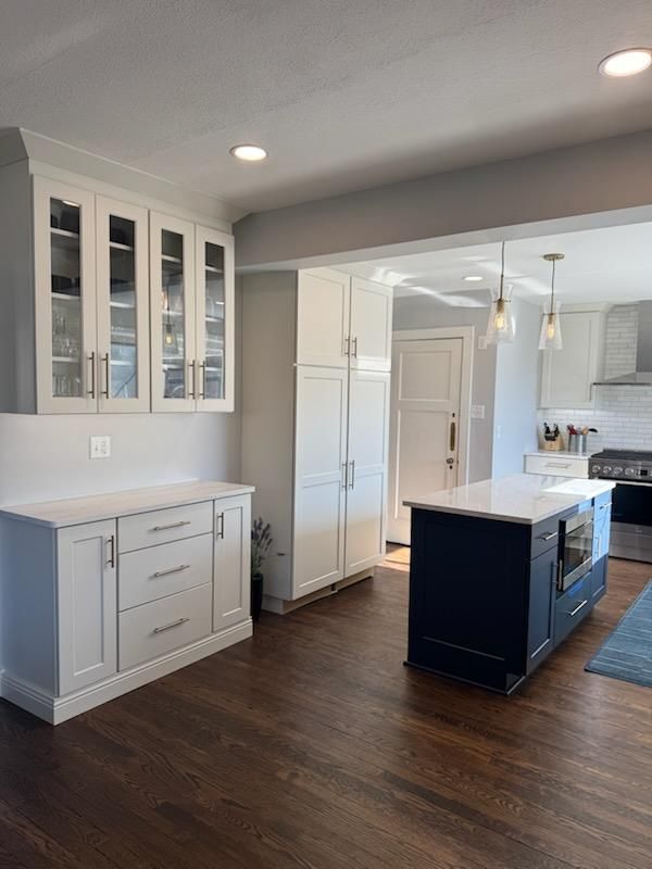 Bright modern kitchen with white cabinets, dark wood floors, and a central island.