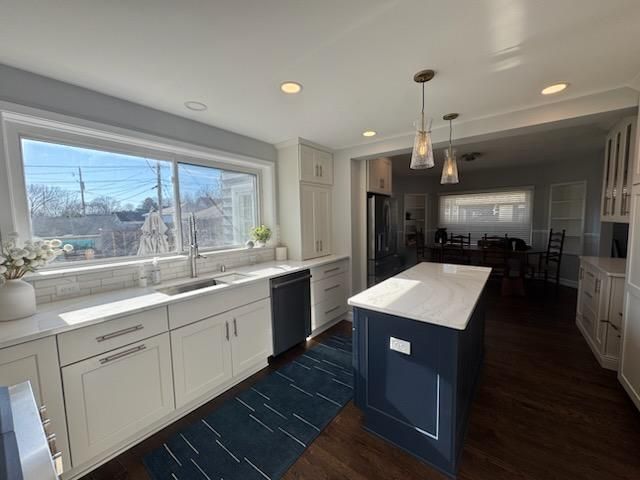 Bright modern kitchen with white cabinets, large window, and blue island countertop