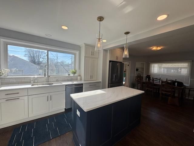 Modern kitchen with white cabinets, dark island, and large window overlooking a snowy yard
