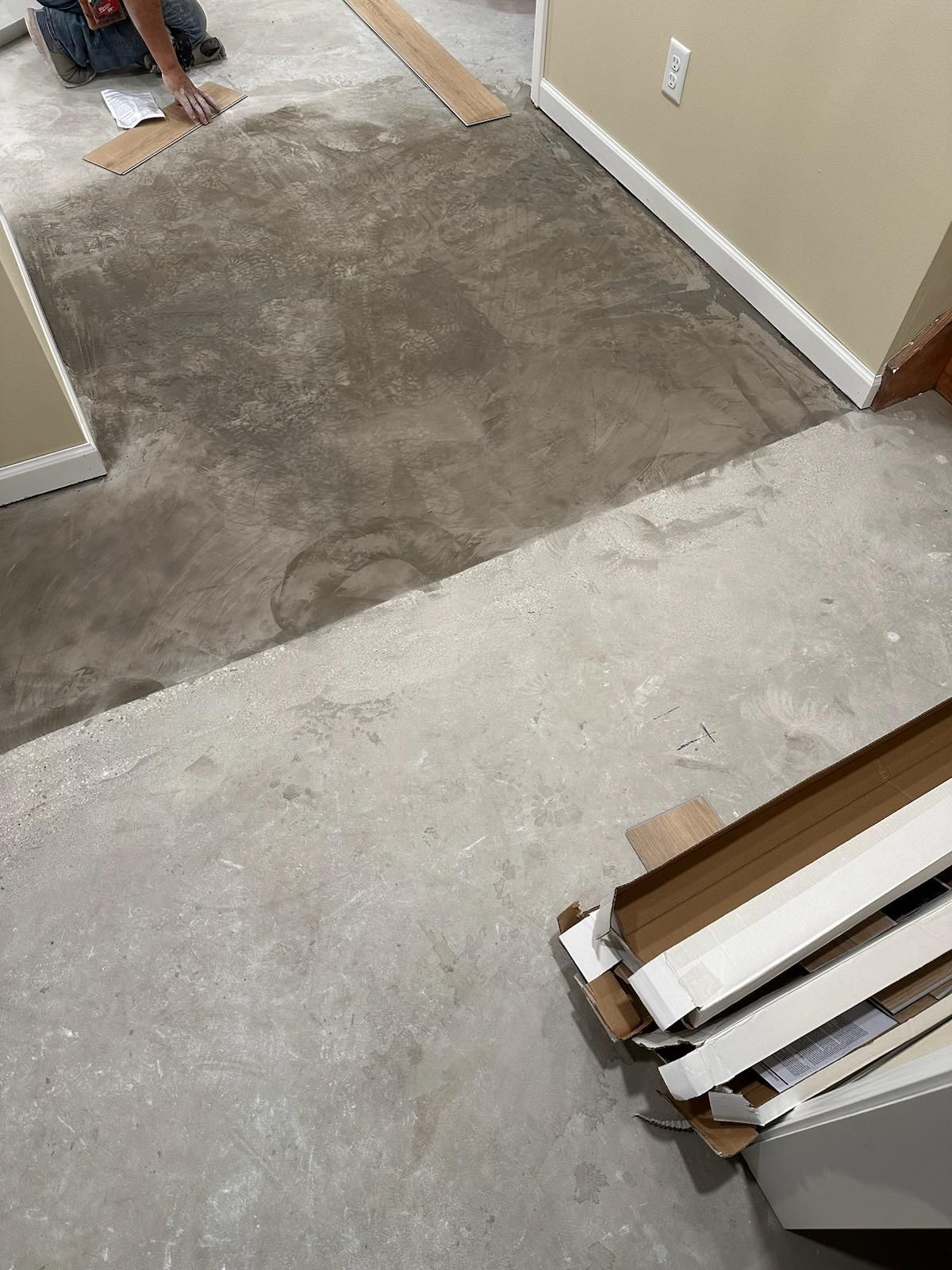 Carpet remnant and bare subfloor in a doorway during renovation, with trim boards stacked nearby